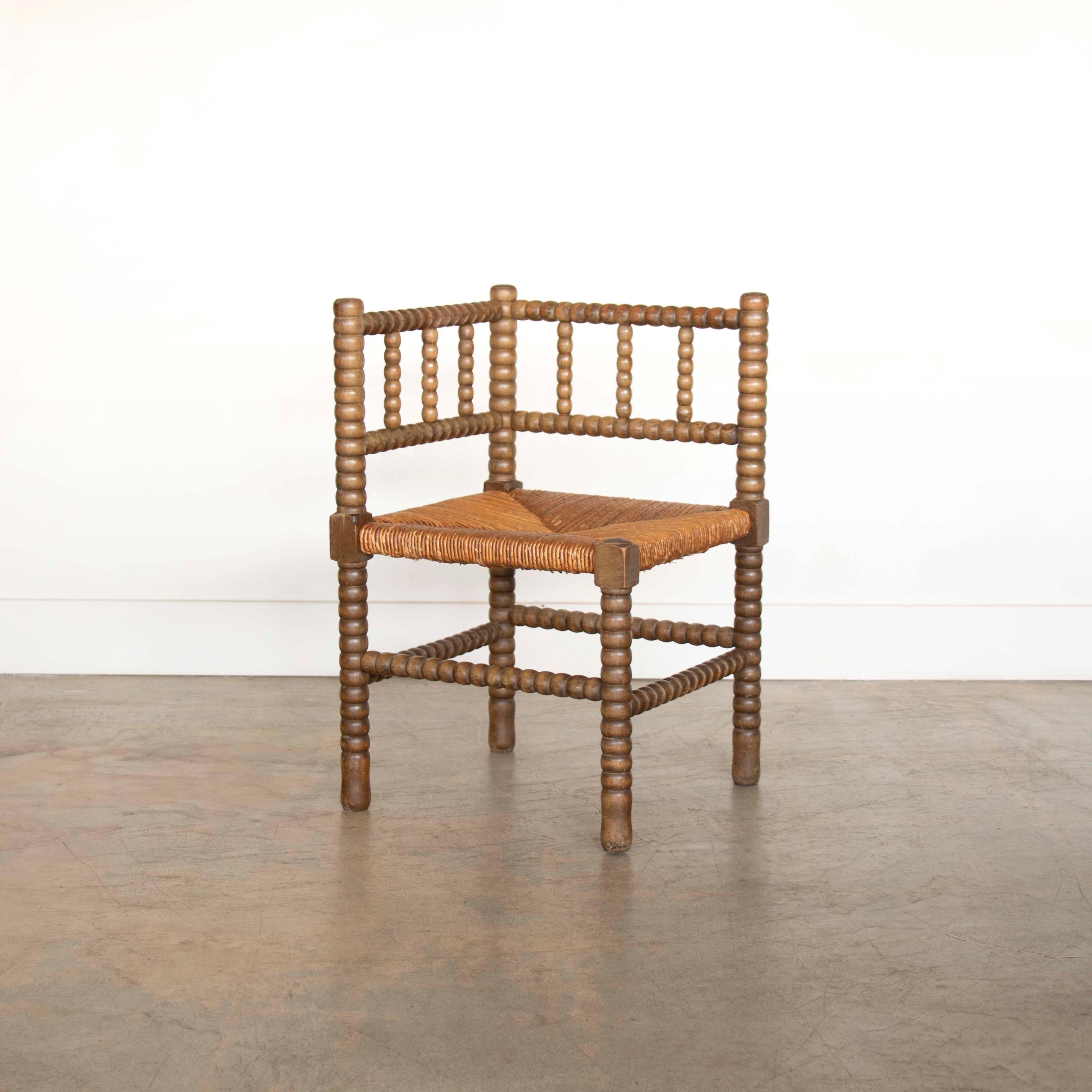 Vintage wood and woven corner chair from France, 1940's. Original dark wood bobbin frame with woven rush seat. Small scale with great patina and age. 