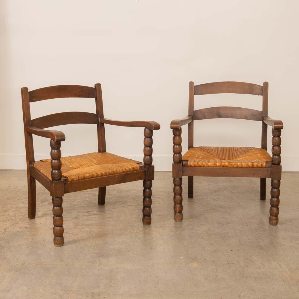 Wonderful carved wood armchair from France, 1940s. Beautiful carved bobbin wood legs and frame. Original woven rush seat. Original finish shows great age and patina. Two available, sold individually.