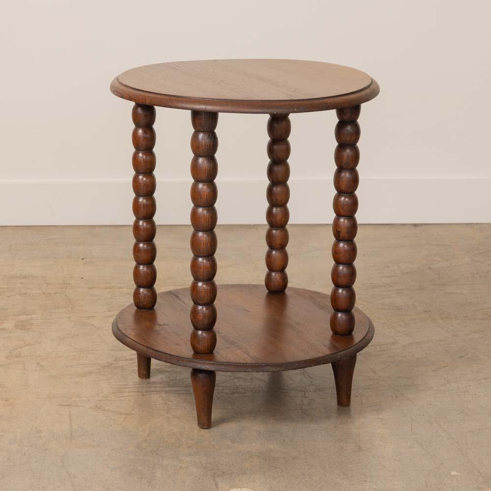 Ravissante table d'appoint à deux niveaux en bois sculpté, France, années 1940. Plateau circulaire avec étagère inférieure et quatre pieds sculptés en forme de fuseau. La finition d'origine présente une belle patine d'âge. 