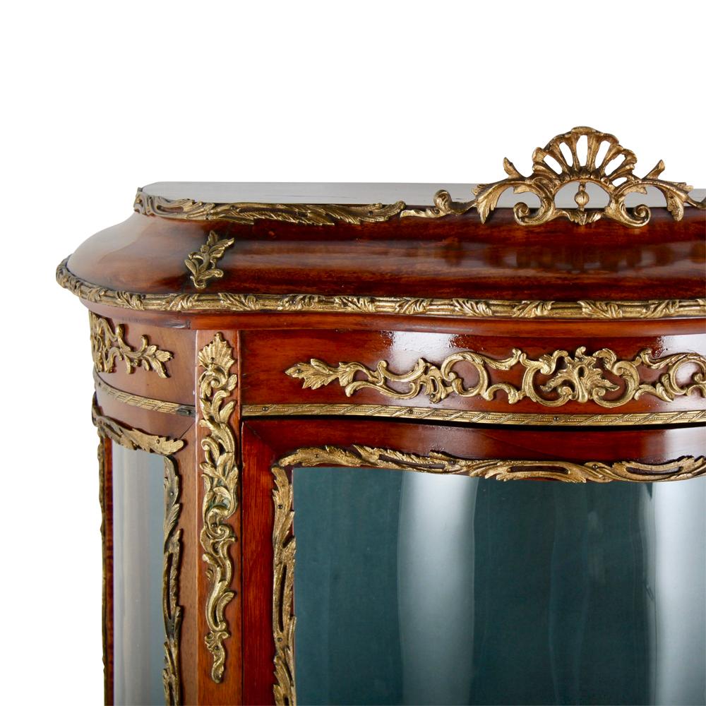A single-door French Louis XV-style mahogany 'bombe' vitrine with curved glass door and sides, the case accented with gilt mounts throughout.
 