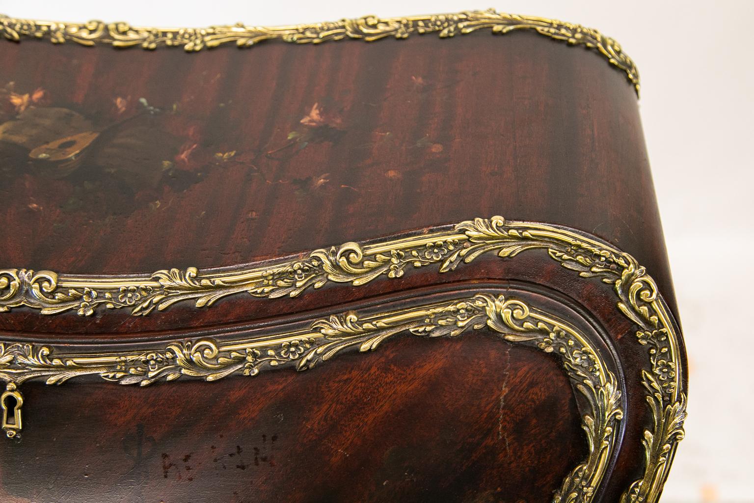 French Bombe slant front ladies desk, the slant front is painted with a figure of a woman holding a stylized caduceus in her left hand, and a dove in her right hand. The top is painted with musical motifs including a mandolin, music score, and