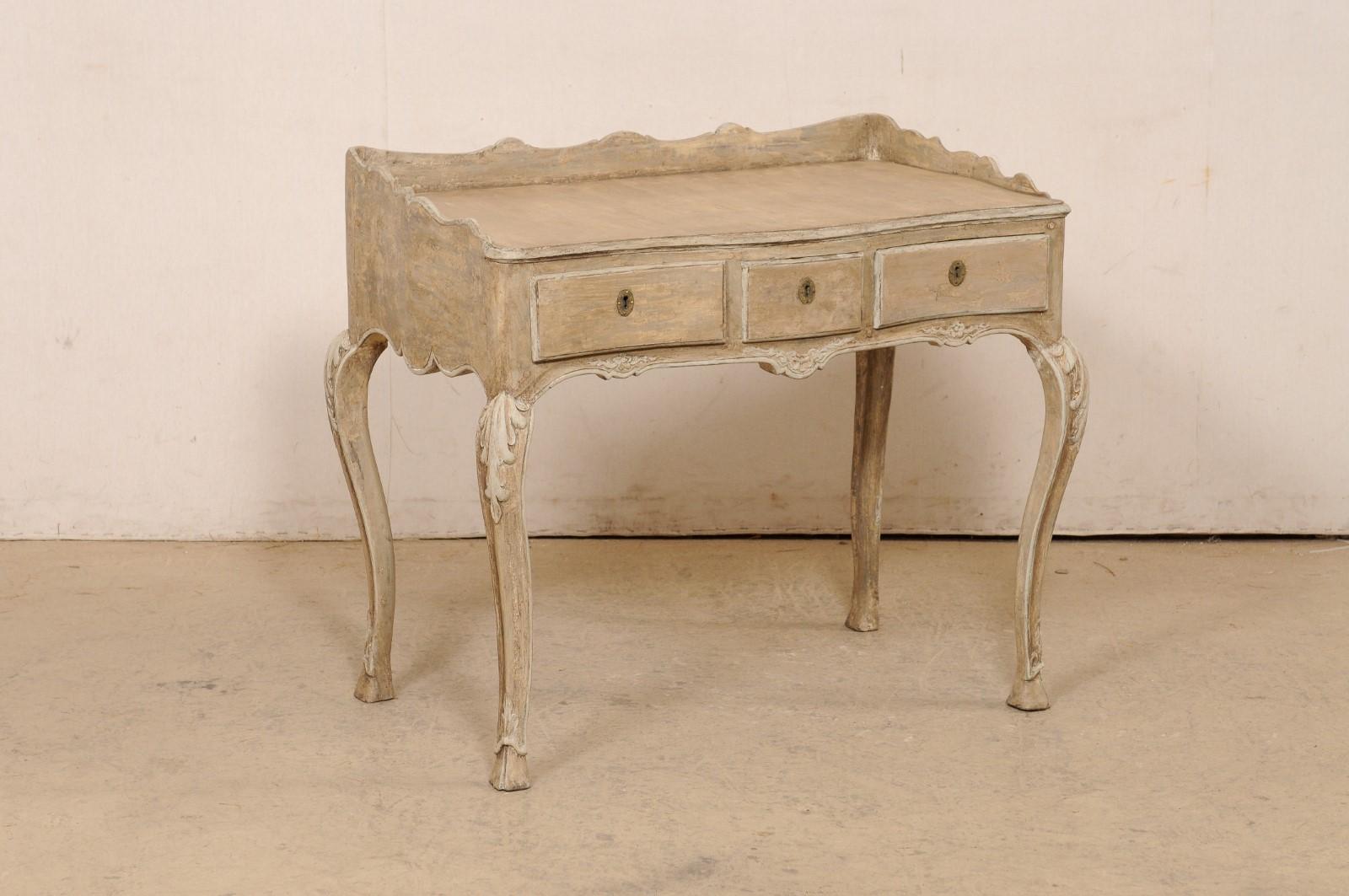 A French painted wood small-sized writing desk from the turn of the 18th and 19th century. This antique table from France has a rectangular-shaped top with a raised and beautifully scallop-carved lip which frames in the back and sides. The apron