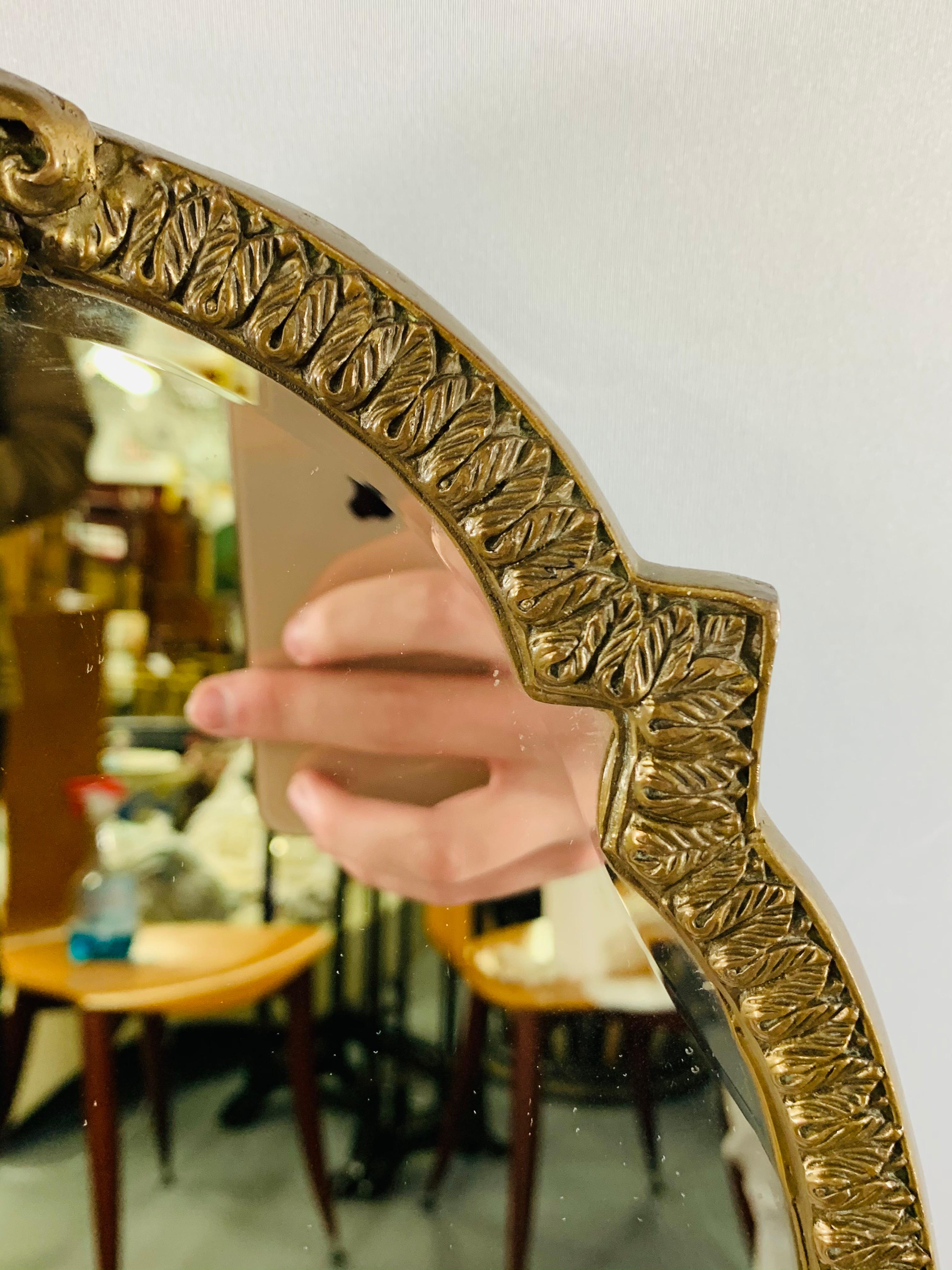 Miroir de courtoisie Louis XV de la fin du XIXe siècle. Le miroir en bronze sculpté présente des détails impressionnants avec deux chérubins de chaque côté portant un chandelier rond. Le cadre du miroir est décoré d'un motif de feuilles et couronné