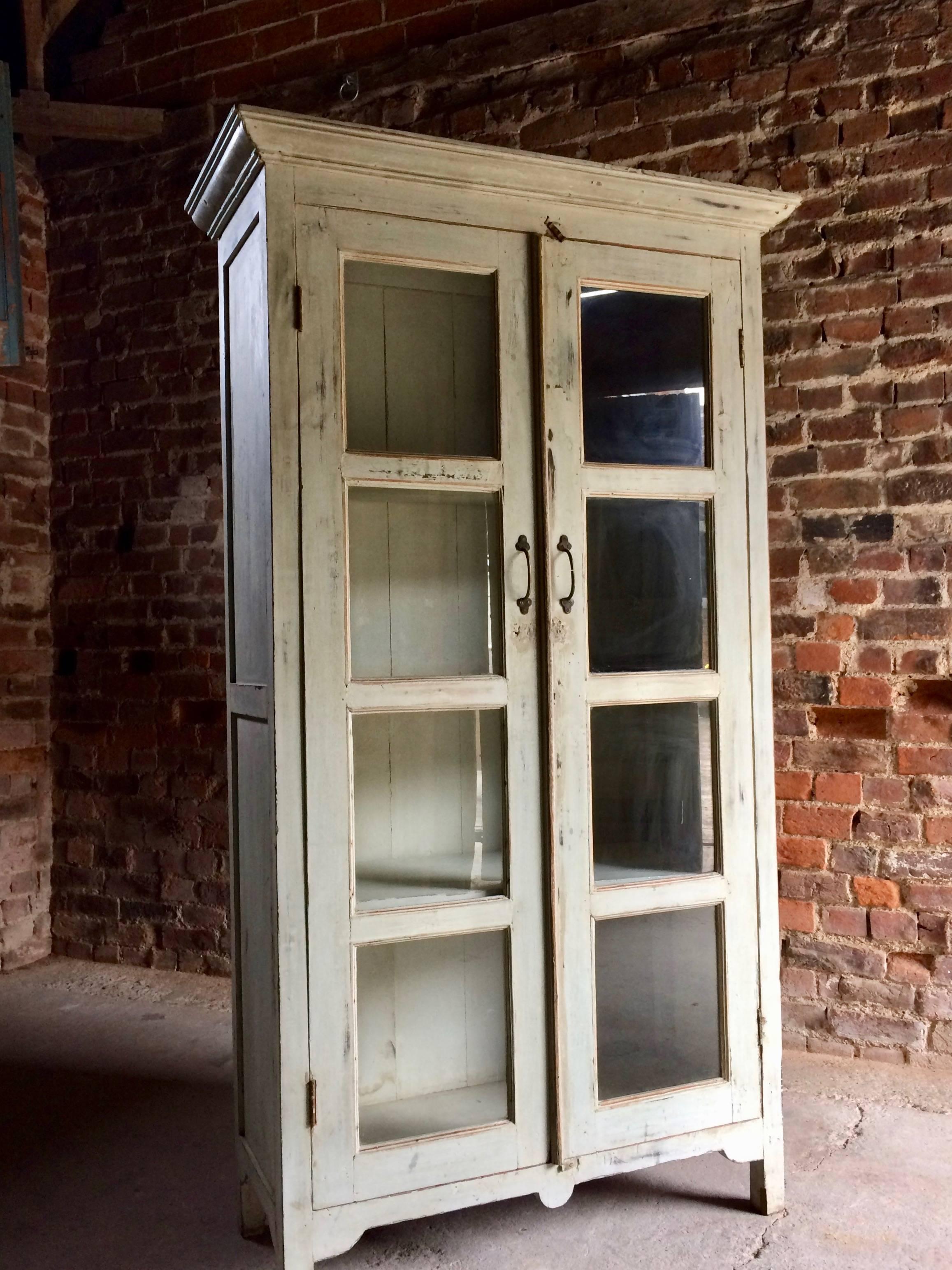 Stunning antique French bookcase display cabinet, circa 1880s, the corniced top over two glazed panel doors each with four sections, three removable shelves within, standing on bracket feet, distressed painted finish all-over, looks