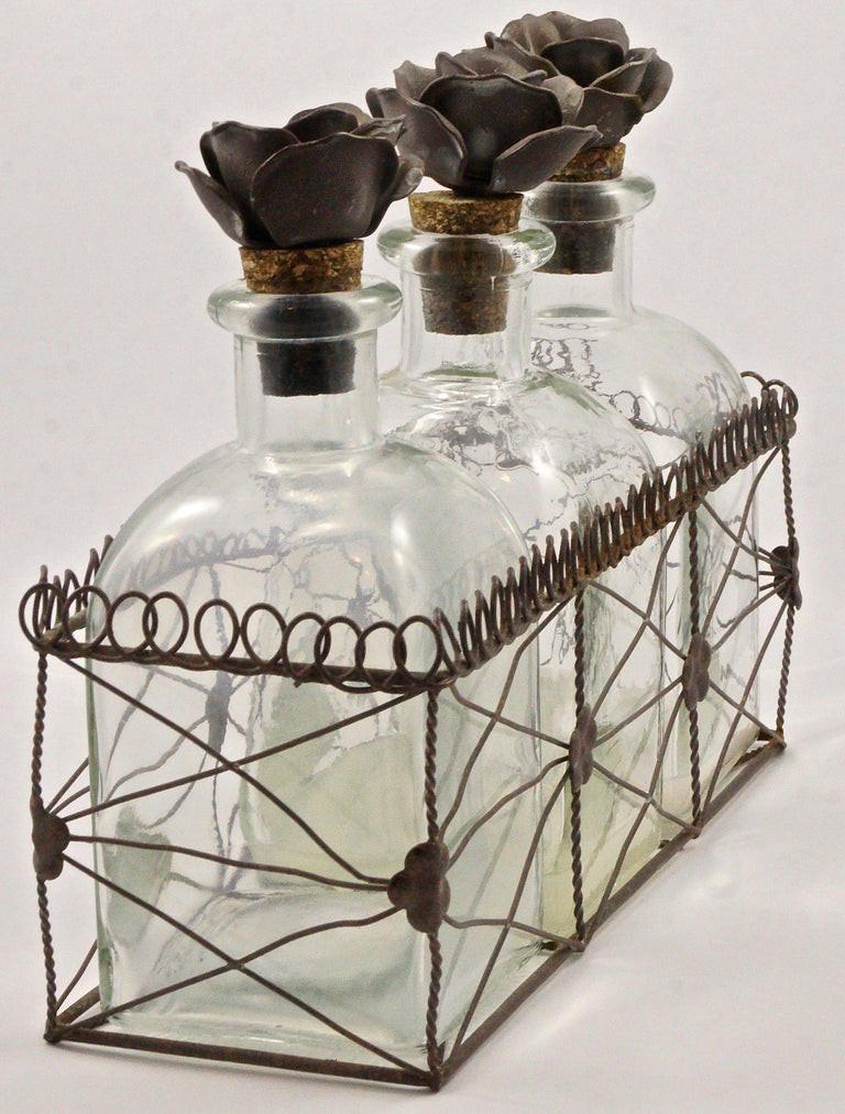 Lovely set of three French storage bottles with metal flower and cork stoppers, contained in an intricate metal wire basket holder. The flowers and basket are painted in mushroom brown with lighter coloured flecks. The bottles are made from old