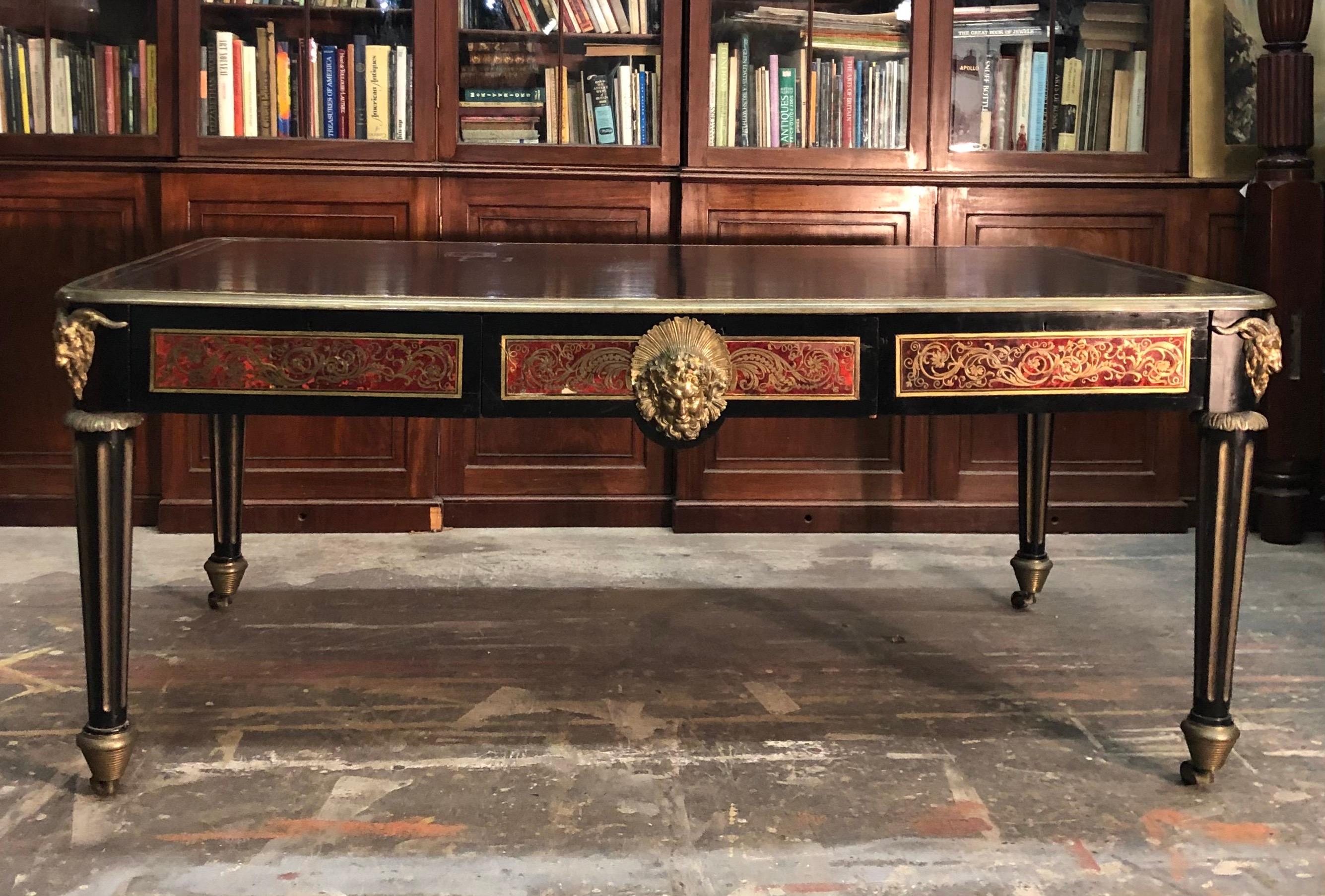 Exceptional French Boulle bureau plat has the English feel of a library table with the four rams head mounted bronze fluted legs terminating in a bronze caster stylized as a beehive. The Boulle marquetry writing desk is finished on both sides with