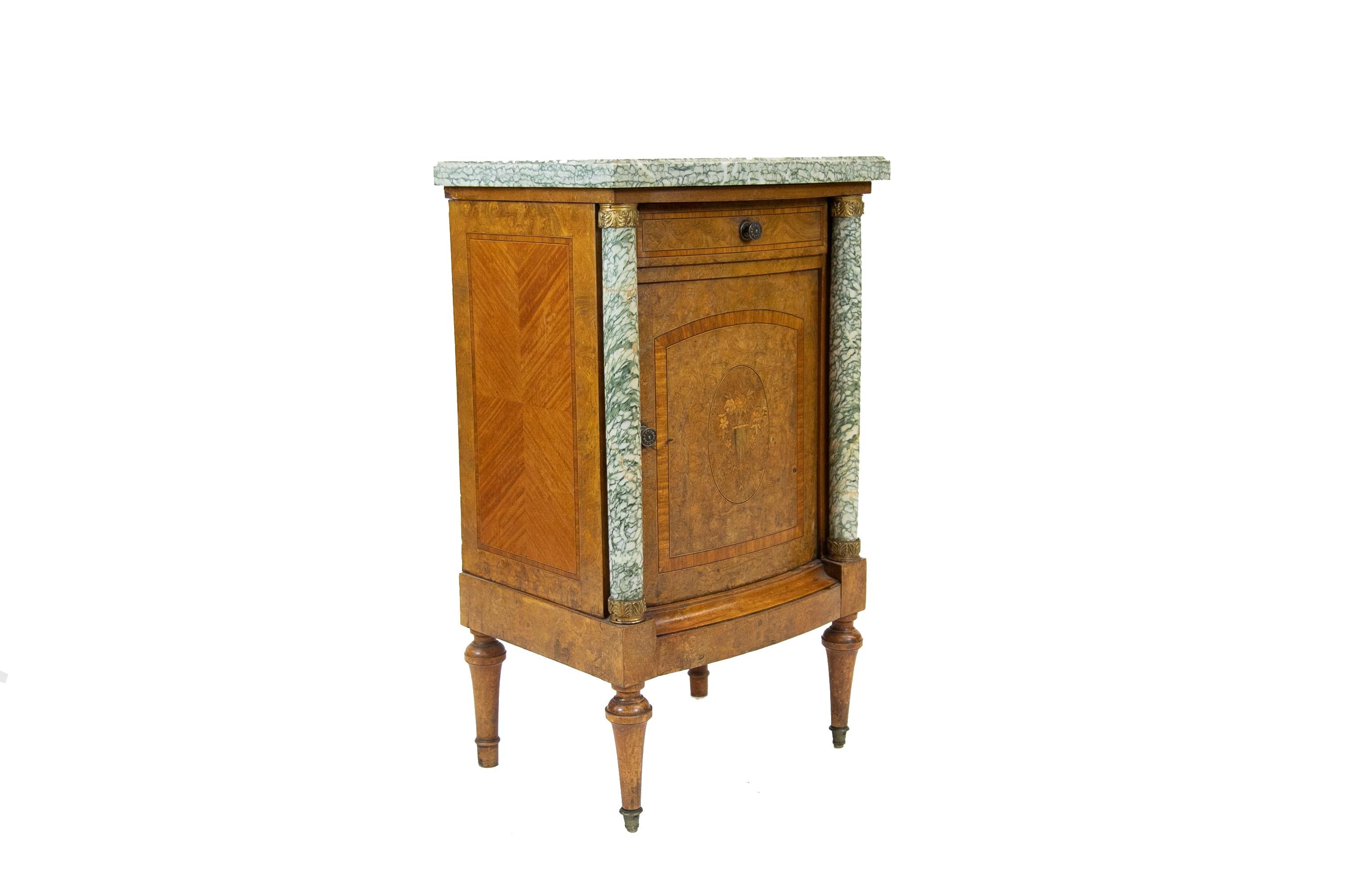 French bow front burl walnut marble-top cupboard, has marble columns with brass capitals and bases; the door is cross banded and inlaid with a satinwood floral urn. Inlaid panels are crossbanded on the sides, two interior shelves. Turned legs end in
