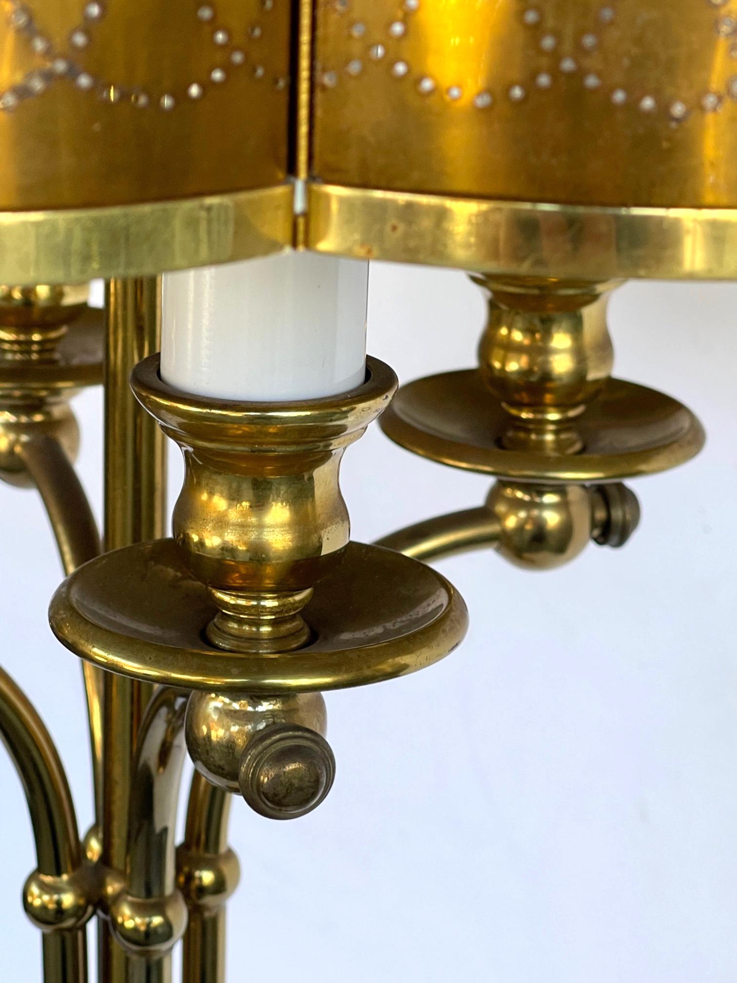 each out-scrolled candle arm emanating from a vasi-form base; fitted with the original scalloped brass shade with pierced decoration