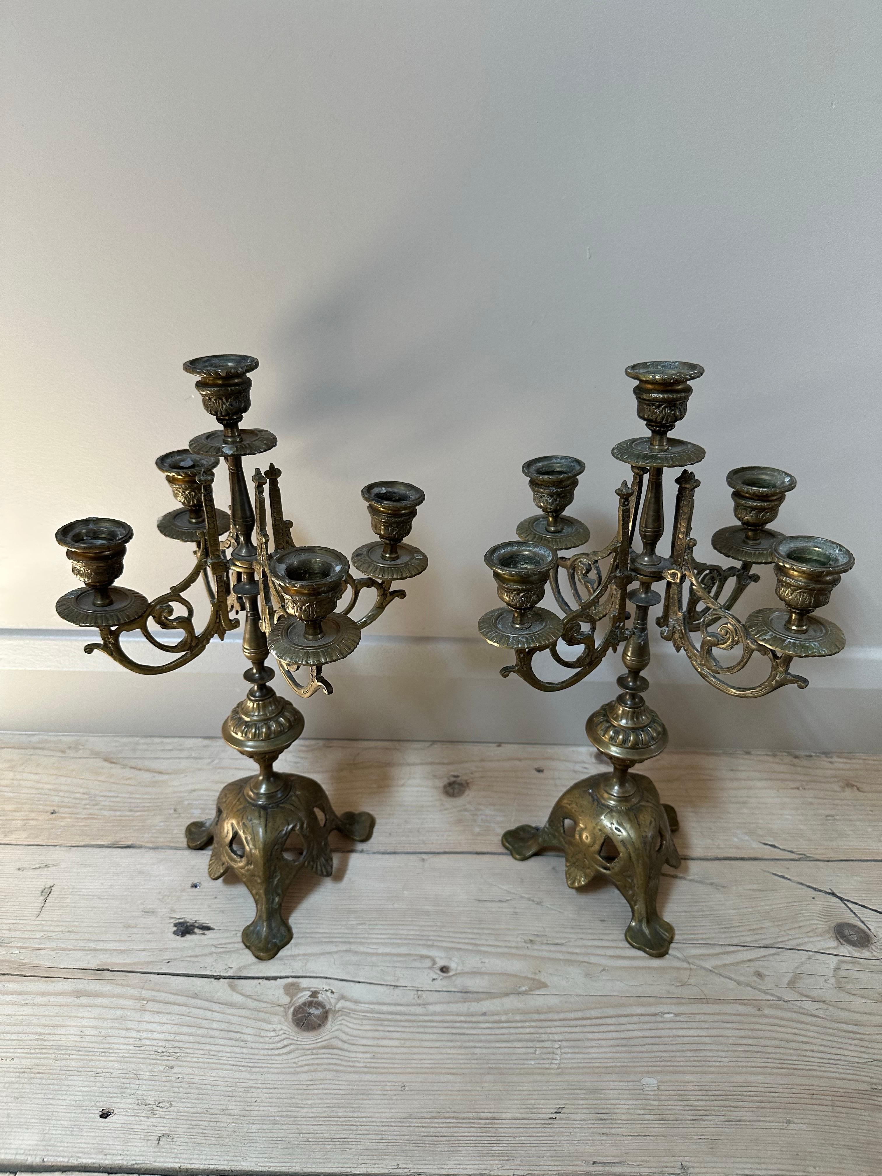 A stately and elegant pair of five-arm candelabras, crafted in solid brass and likely French in origin, dating to the late 19th century. These pieces capture the grandeur of neoclassical design with ornate flourishes, voluted arms, and a richly cast