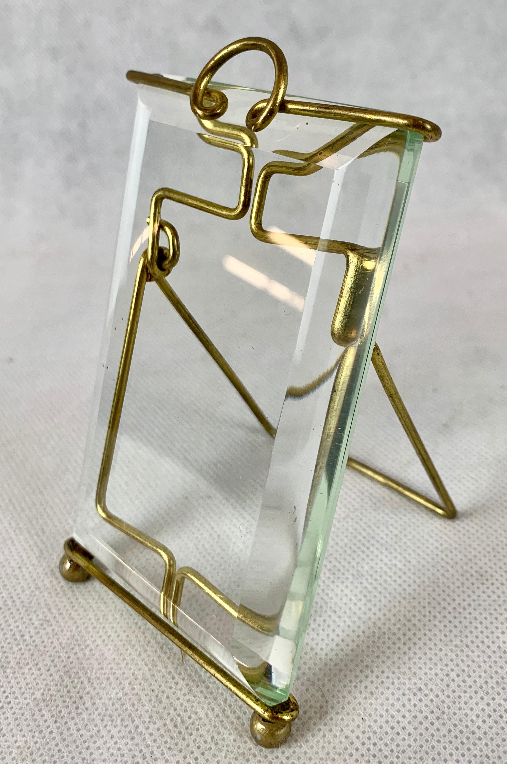 Late 19th century unusual brass and beveled glass photo frame. The thick piece of glass is easily removed by pulling up on the wire. The brass wire by itself creates an interesting image. The frame rests on two brass ball feet. You place the photo