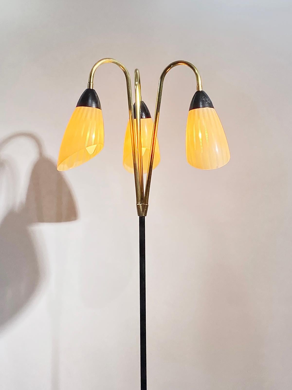 Beautiful mid-century floor lamp, in the style of Stilnovo featuring three tulip glass shades, on a brass and black metal structure.
