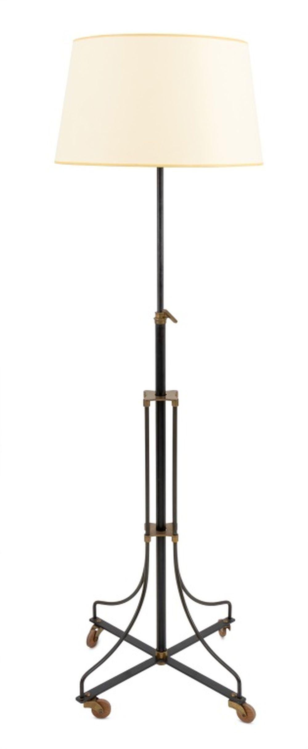 Lampadaire industriel français en laiton et métal patiné noir, avec support central réglable et quatre pieds en araignée reliés par un brancard en X sur roulettes en bois. 65.5