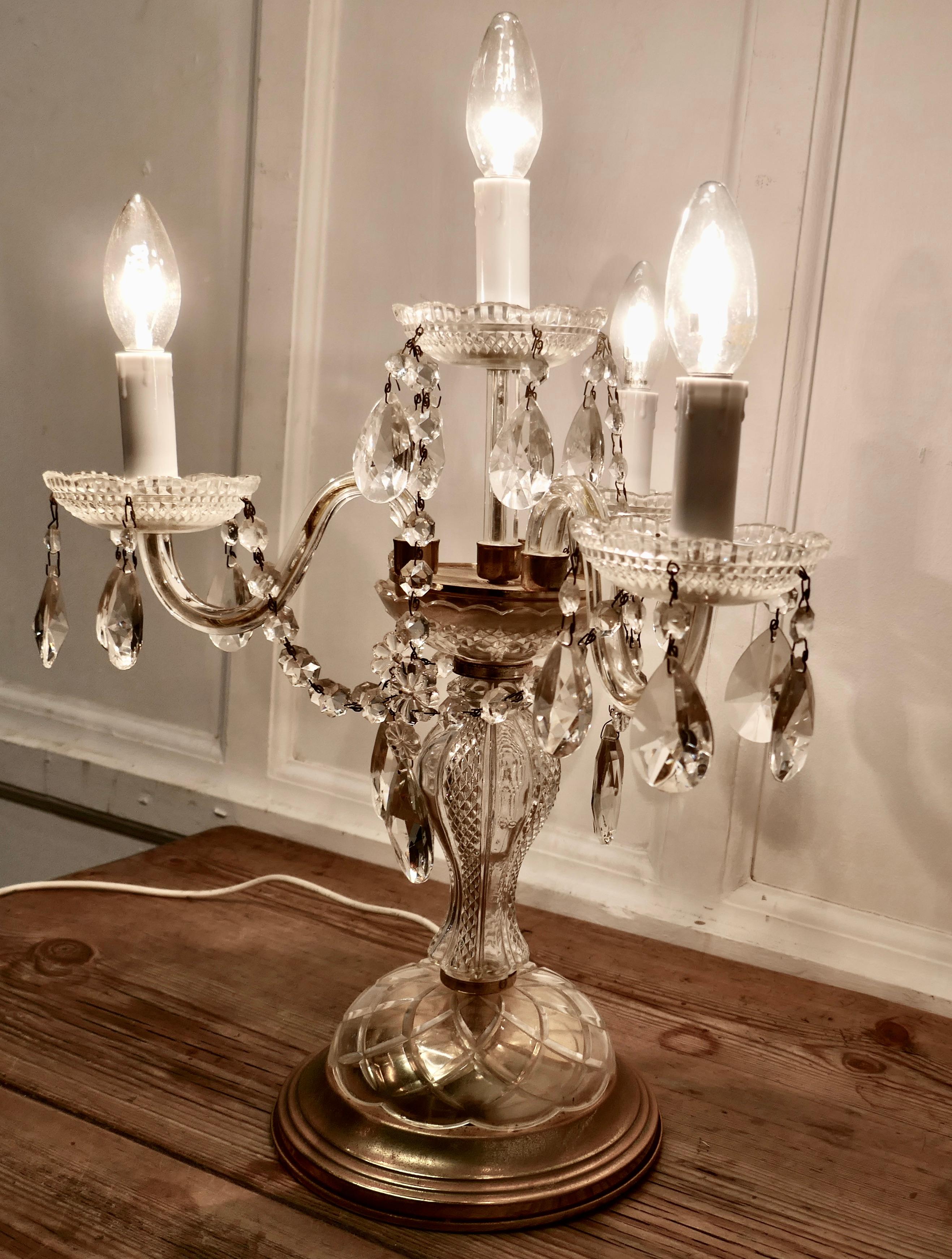 French brass and crystal chandelier table lamp, girandole

This is a lovely piece, the lamp is lit with 3 lamps, it has a decorative brass base with a glass upright central column supporting a superb brass and crystal lustre hung chandelier

The