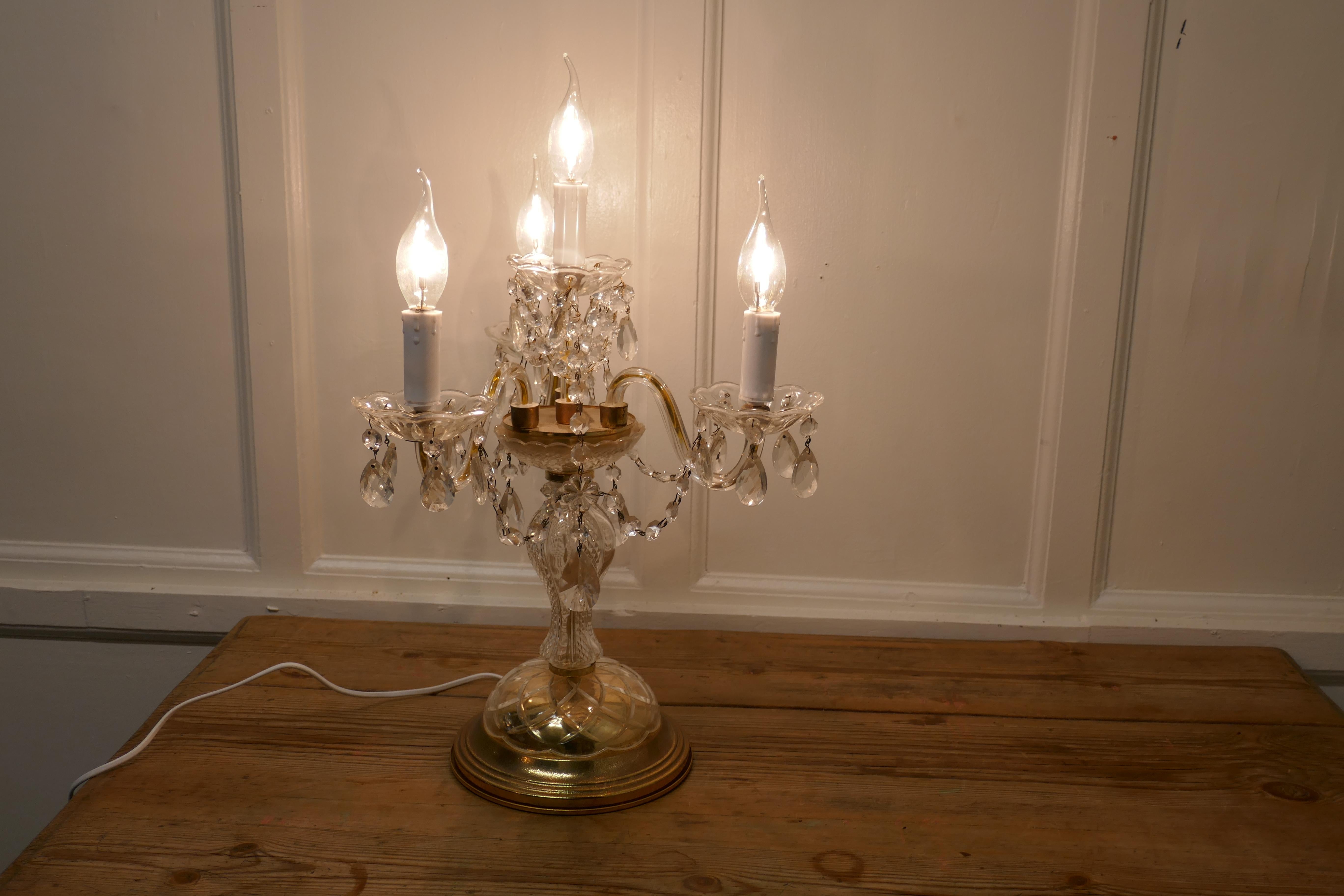 Lámpara de sobremesa francesa de latón y cristal, Girandole

Es una pieza preciosa, se enciende con 4 lámparas, tiene una base decorativa de latón con una columna central vertical de cristal que sostiene una magnífica araña colgada de latón y