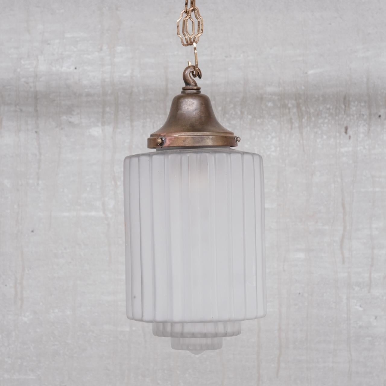 A small stepped brass and glass pendant. 

France, c1930s. 

Opaque glass, stepped at the base. 

No ceiling rose or chain was retained but these are easily sourced online. 

Since re-wired and PAT tested.

Location: Belgium Gallery.