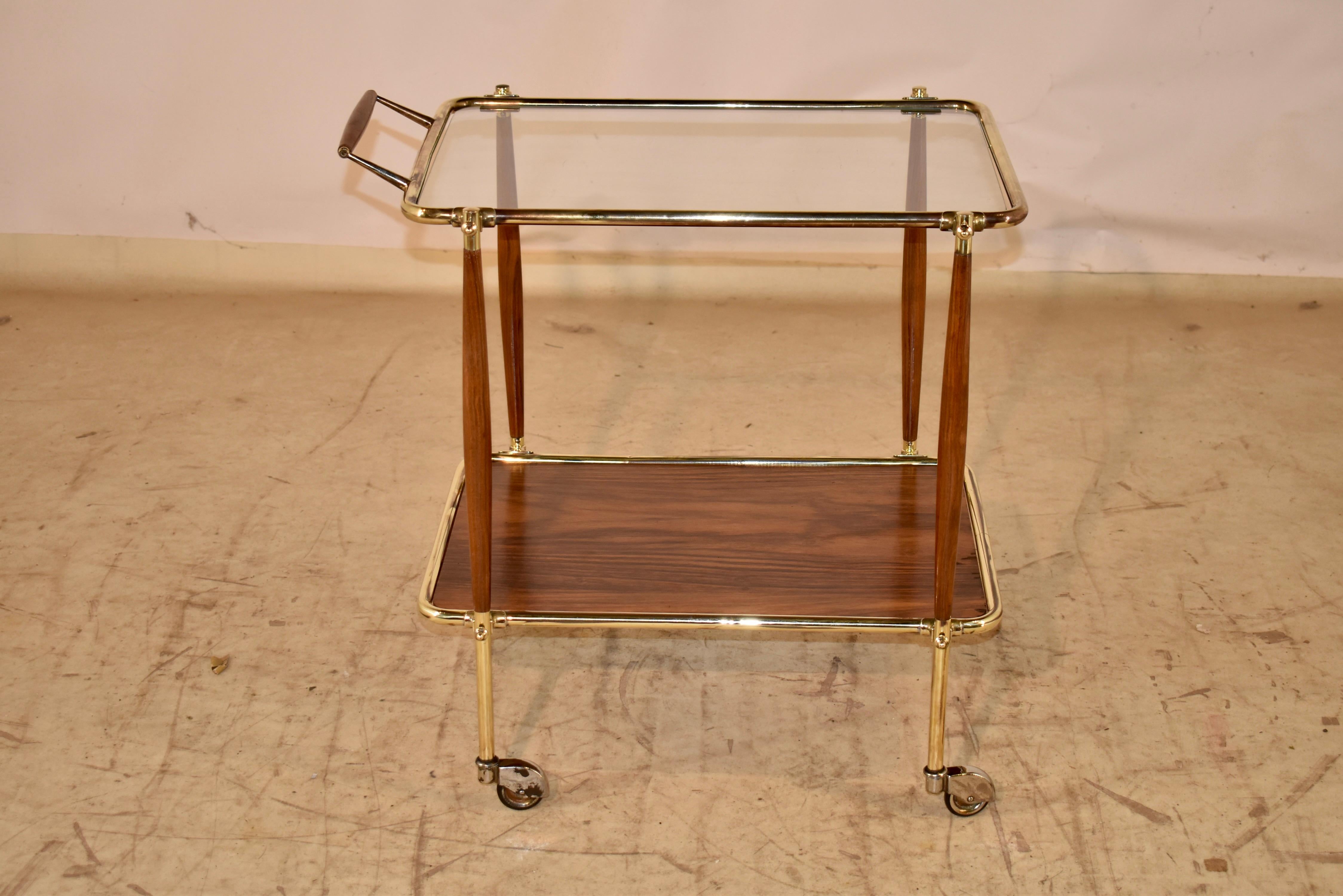 Mid-century modern bar cart made from brass, glass and walnut.  

This is an absolutely stunning bar cart which is elegant in its simplicity.  The handle is made from brass and walnut, following down to the top shelf of the two shelf cart.  The top