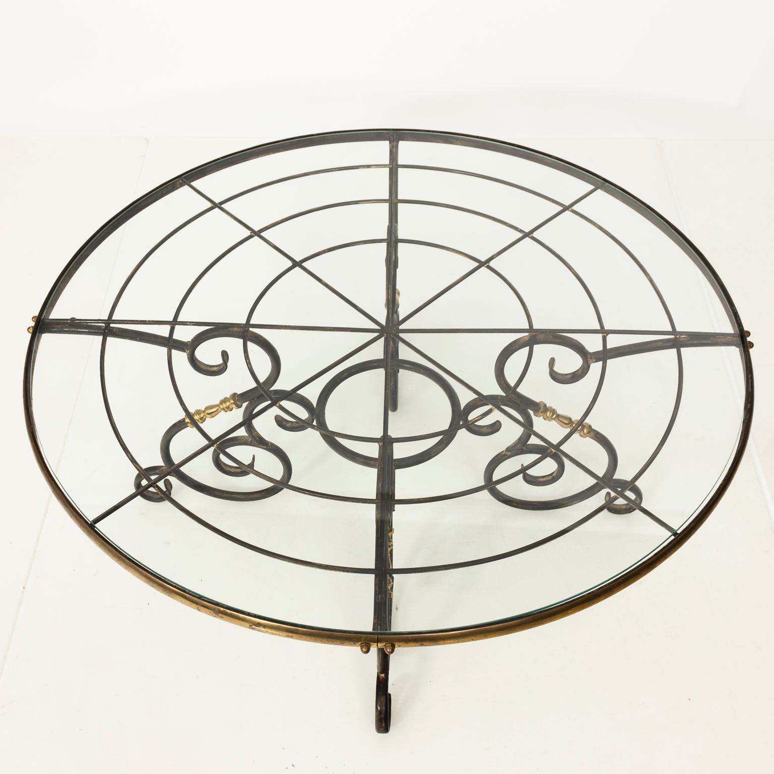 1970s French brass and iron center table with iron S-scroll legs and a glass top.
 