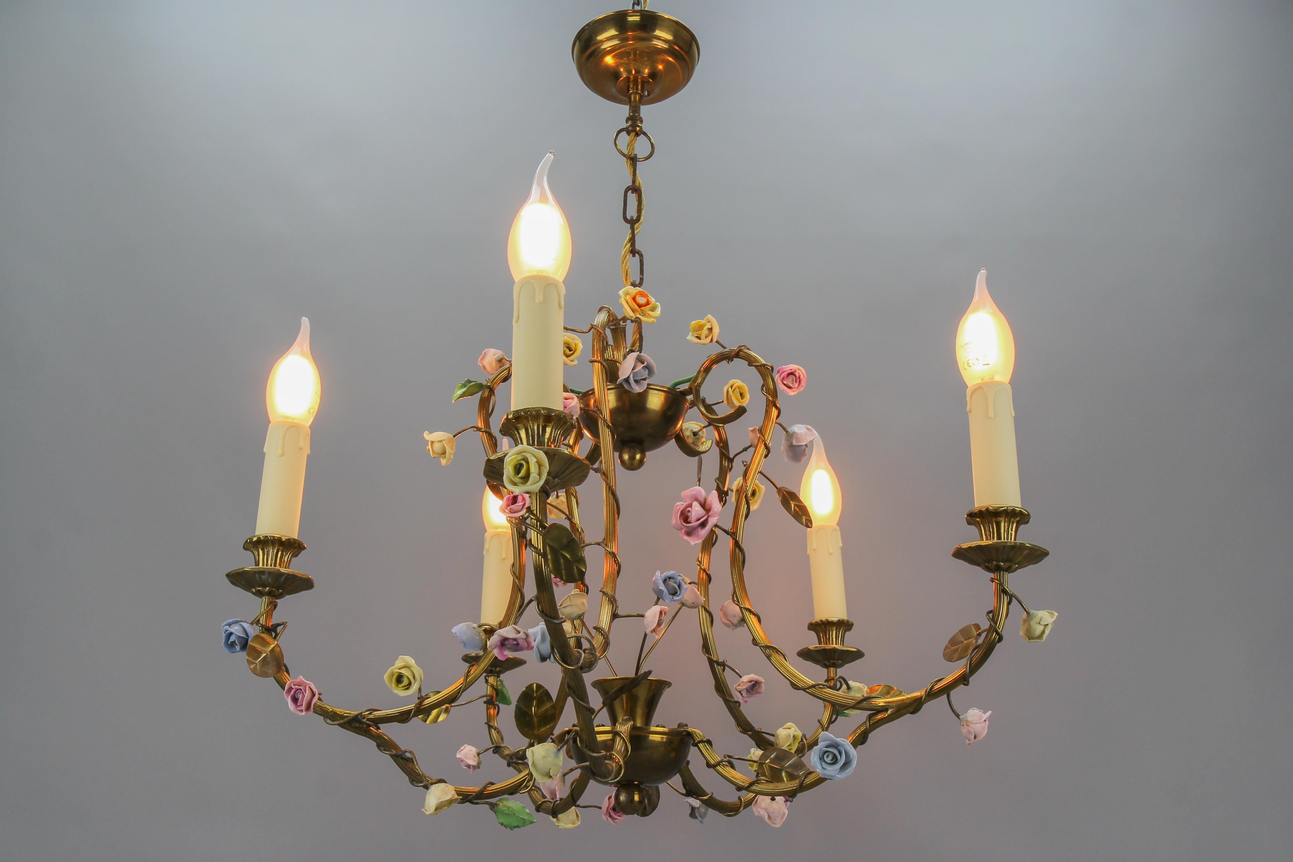 French brass and porcelain flower five-light chandelier, the 1920s.
This adorable chandelier is surrounded by porcelain flowers painted in pastel tones and brass leaves draped around the five branches of the light in a harmonious way. France, circa
