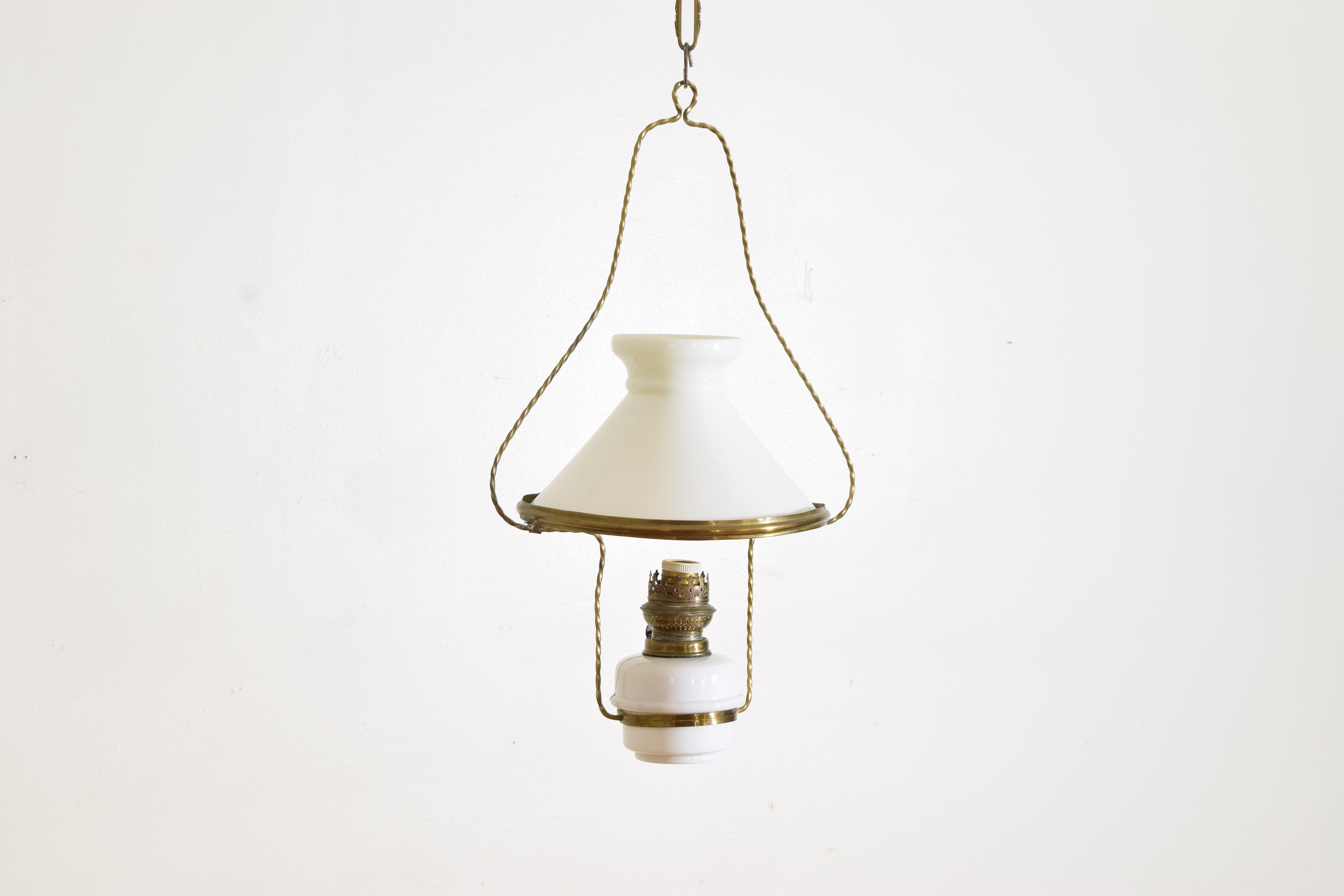 A light and simple lantern with it's original milk glass and brass accents, once an oil lamp with adjustable wick and now electrified with a single socket, the oil reservoir with a repaired crack
