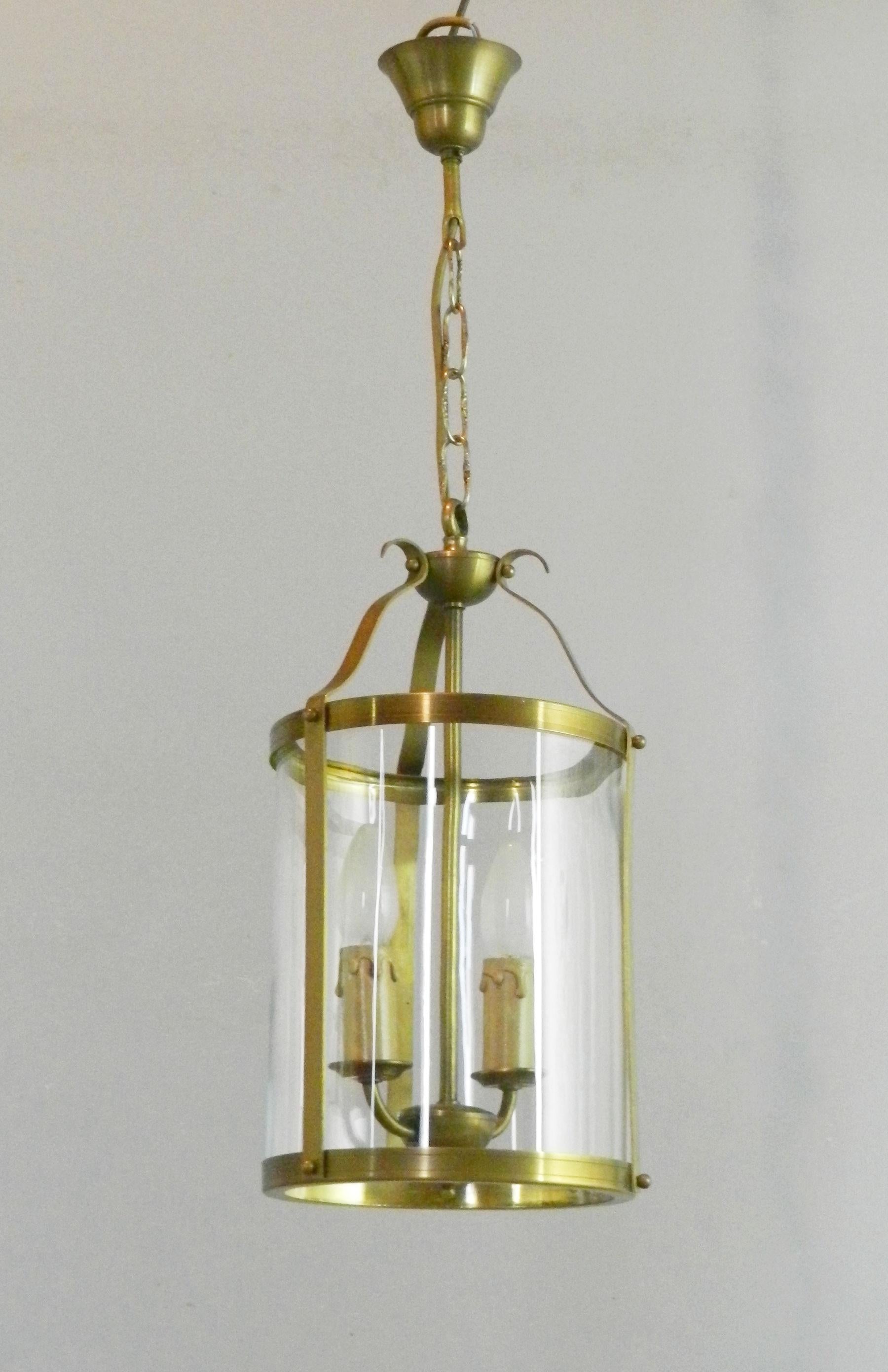 An attractive French brass lantern suspended from its original chain and ceiling fixture, leading down to central twin candle lights.

This is surrounded by a single convex clear glass shade.

The lantern is in full working order and as with all