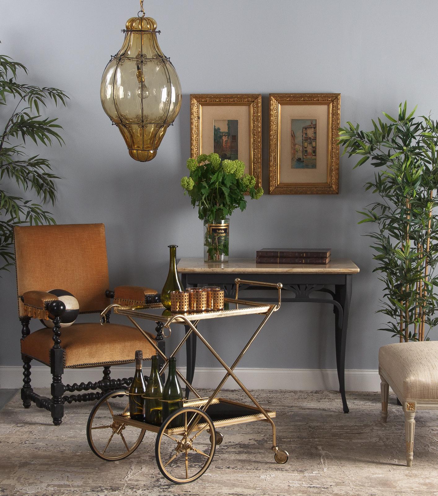 A fabulous two-tiered vintage brass and glass bar cart, French, marked 1972. Plated brass frame with black glass trays, rubber wheels and casters. The tubular frame has cross-body side supports and a slim raised brass handle at the back. Decorative