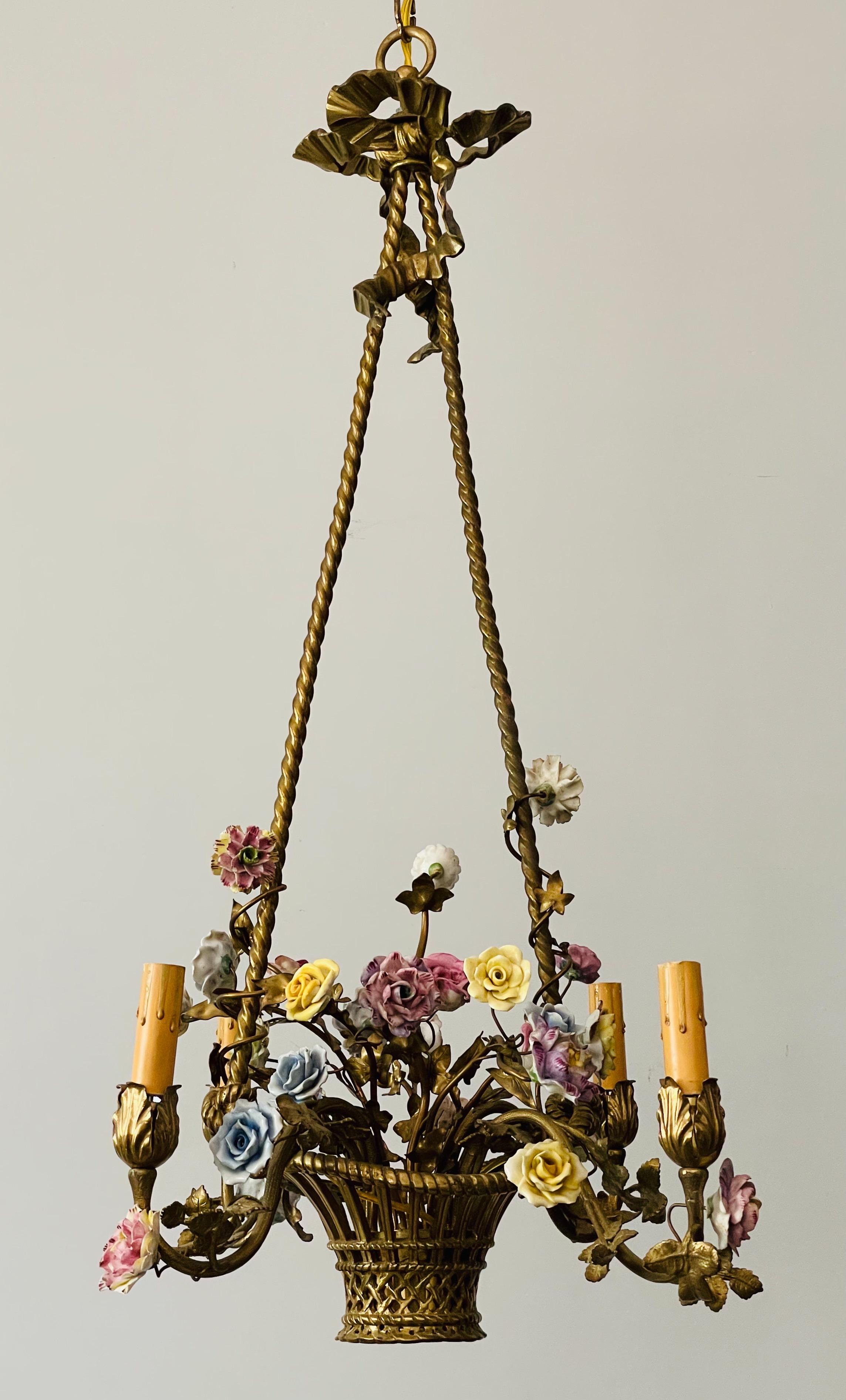Delicate 1940s French brass chandelier in the form of basket filled with porcelain flowers. 

The chandelier is wired and in working condition, it requires 4 candelabra bulbs. A ceiling canopy and 36” chain for installation are included

A