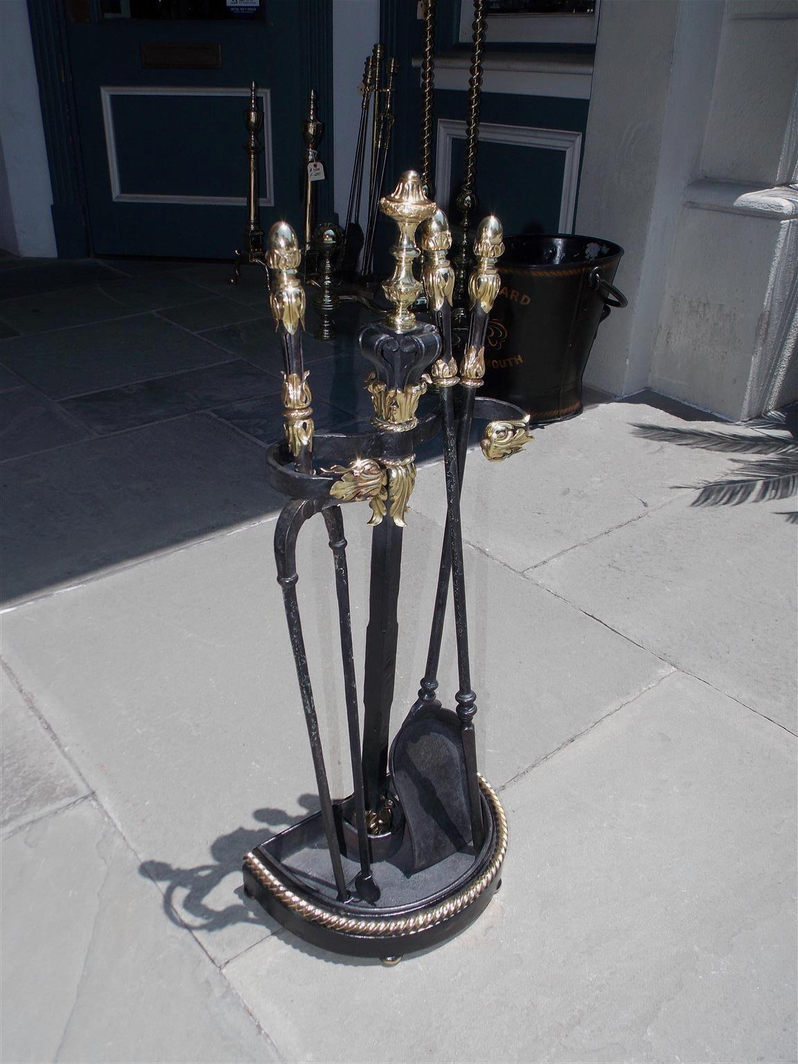 French brass and painted cast iron decorative floral fire place tools resting on the original brass rope motif demilune stand with bun feet. Set consists of poker, tong and shovel, Mid-19th century.