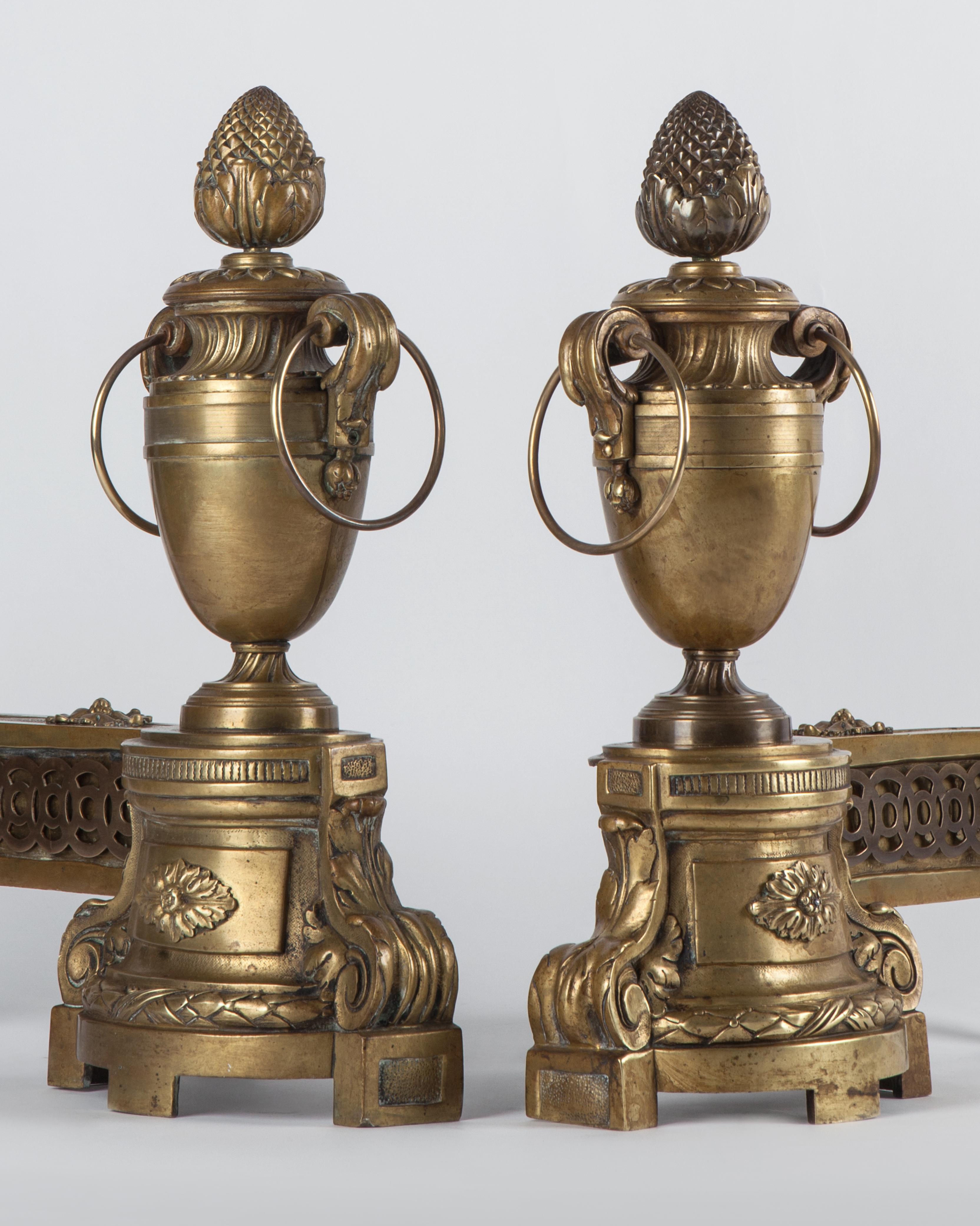 AFP0515
A pair of antique French urn form chenets having finely chased neoclassical details in the bodies with pinecone and flame finials. In their original age-darkened brass finish. Circa 1860.

Dimensions:
Overall: 17-1/2