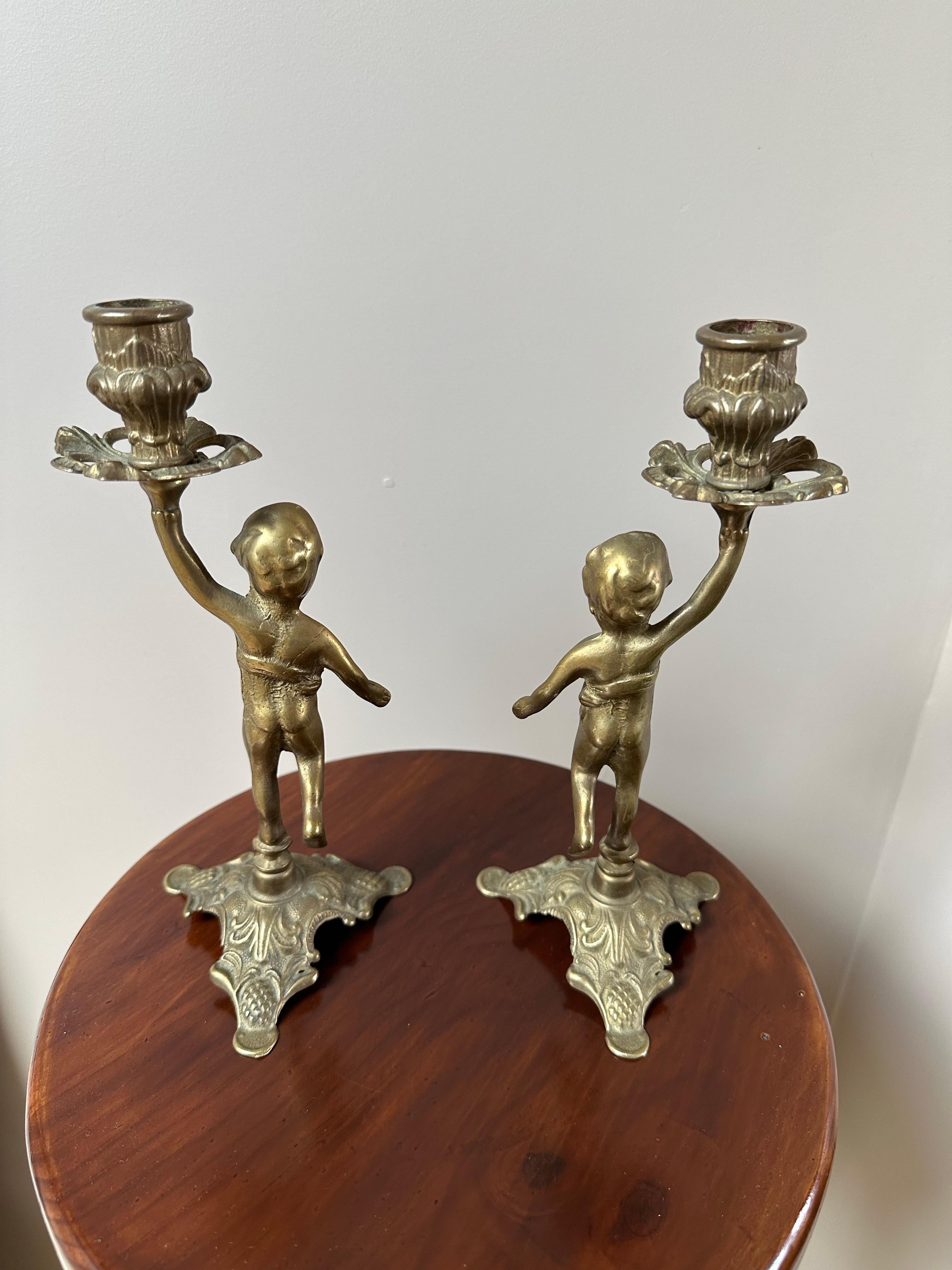 Ti presentiamo una splendida coppia di candelieri a forma di cherubino in ottone vintage, un elegante tributo all'arte classica e alla raffinatezza senza tempo. Ogni figura è finemente fusa e raffigura un cherubino in equilibrio con grazia su un