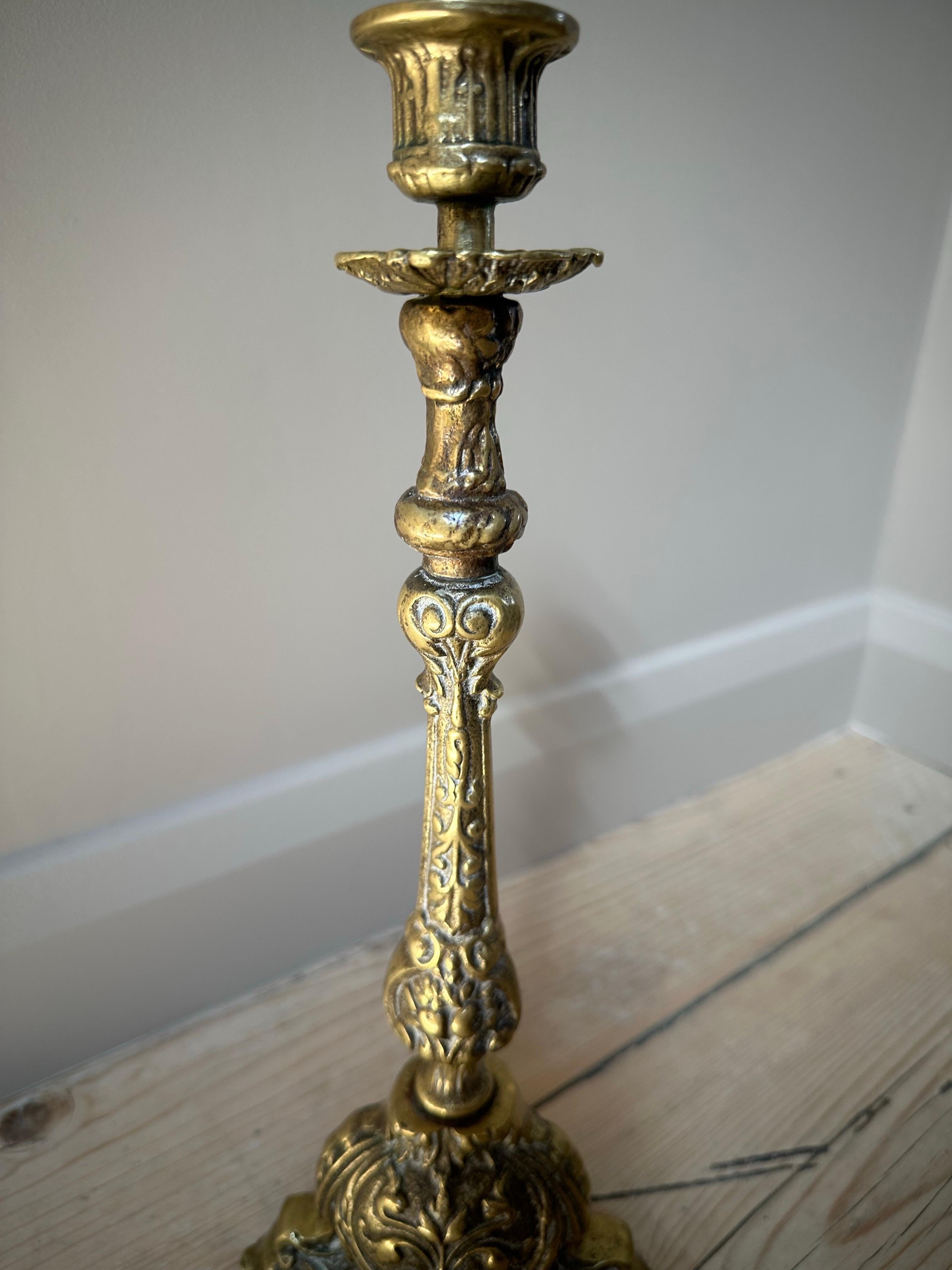 A tall and beautifully detailed French brass altar candlestick from the late 19th century, crafted during the Victorian era (known in France as the Belle Époque).

This classic ecclesiastical piece features a three-sided hollow base with ornate