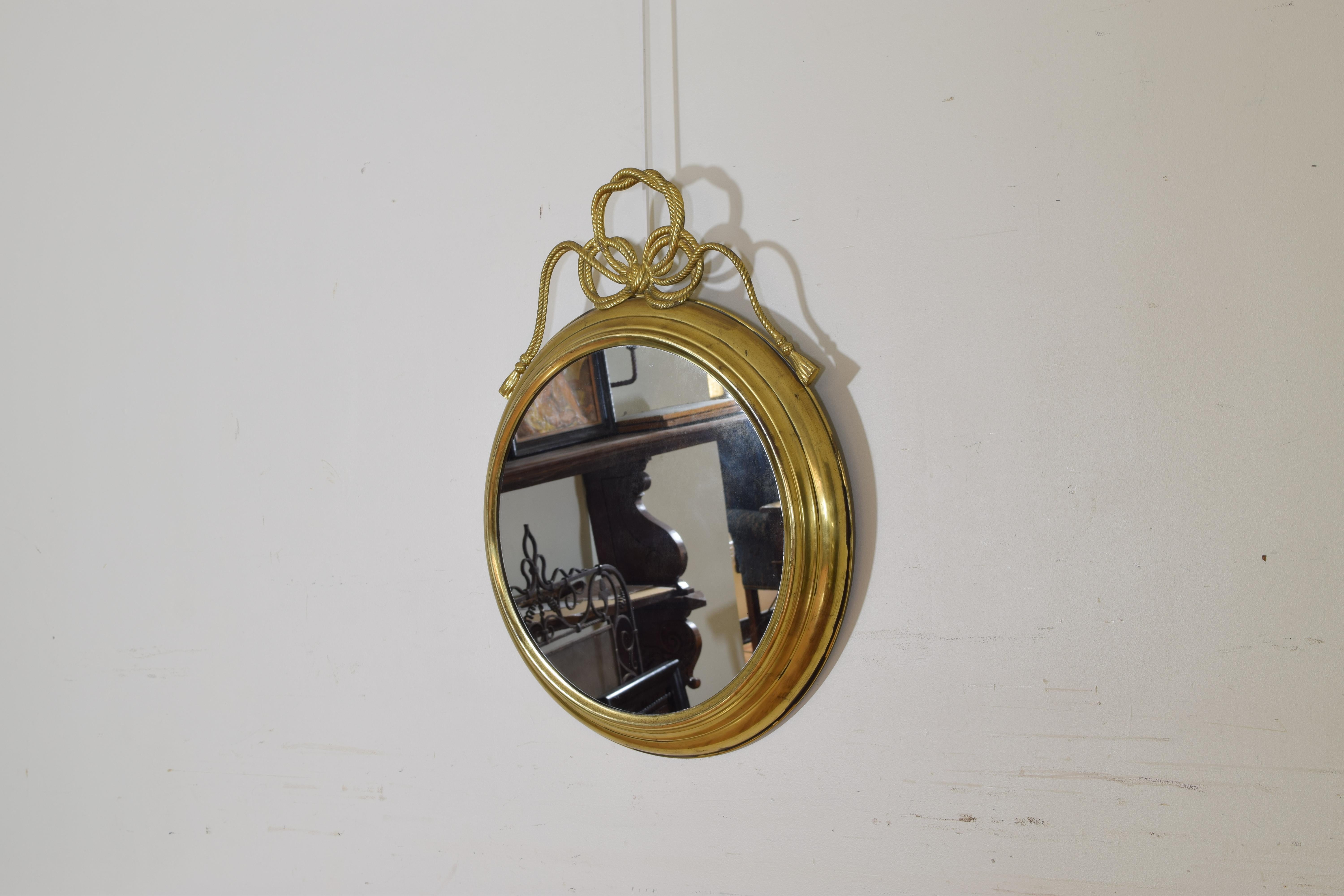 Having a molded brass frame with a double rope braided bow with tassels mounted at top, retaining original mirrorplate.