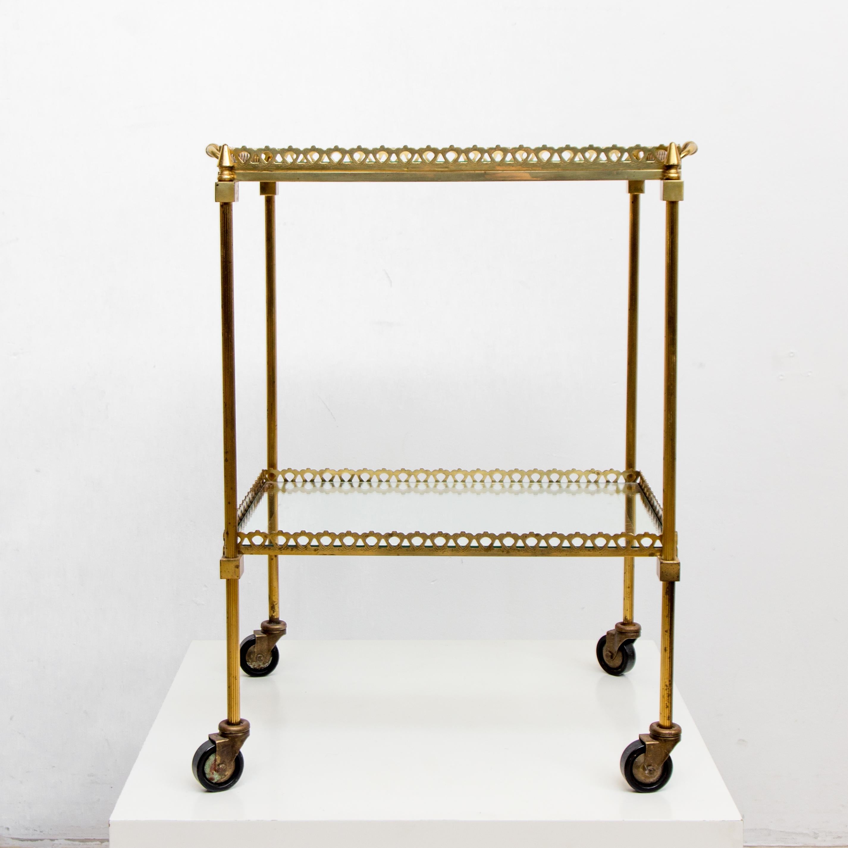 An elegant vintage Directoire style rectangular brass and glass cocktail cart with separate serving tray top, circa 1960s. Glass top is inset and has mirrored edge detail. In good aged vintage condition.