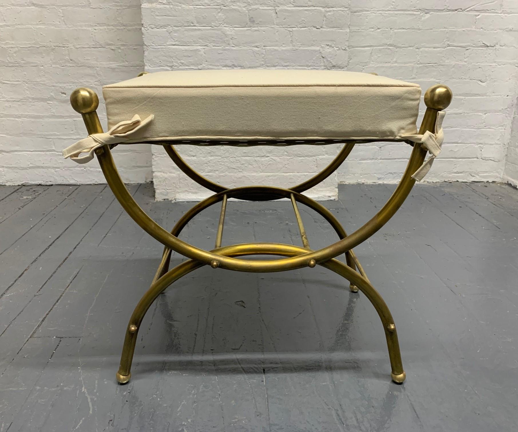 French brass curule bench upholstered in linen with a removable seat. 