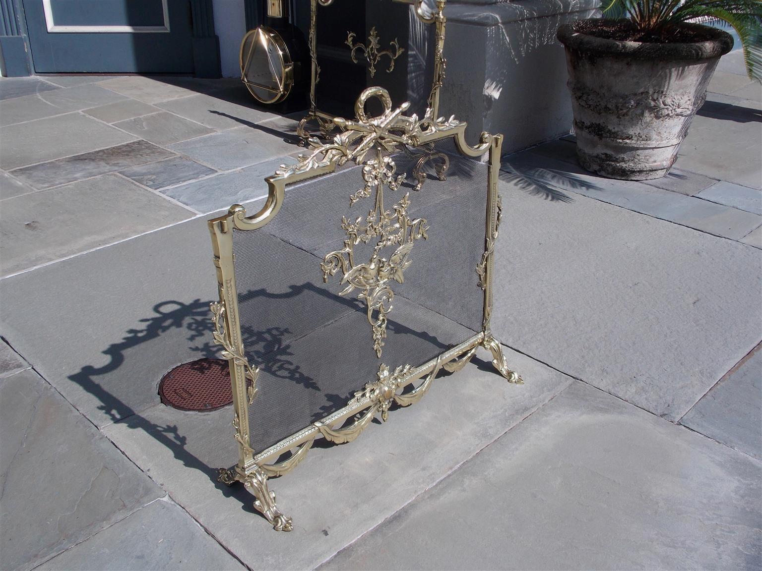 French brass decorative foliage ribbon and bird free standing fireplace screen with centered laurel wreath torchere handle, flanking intertwined fluted floral side columns, lower connecting swags, and resting on the original scrolled acanthus feet,