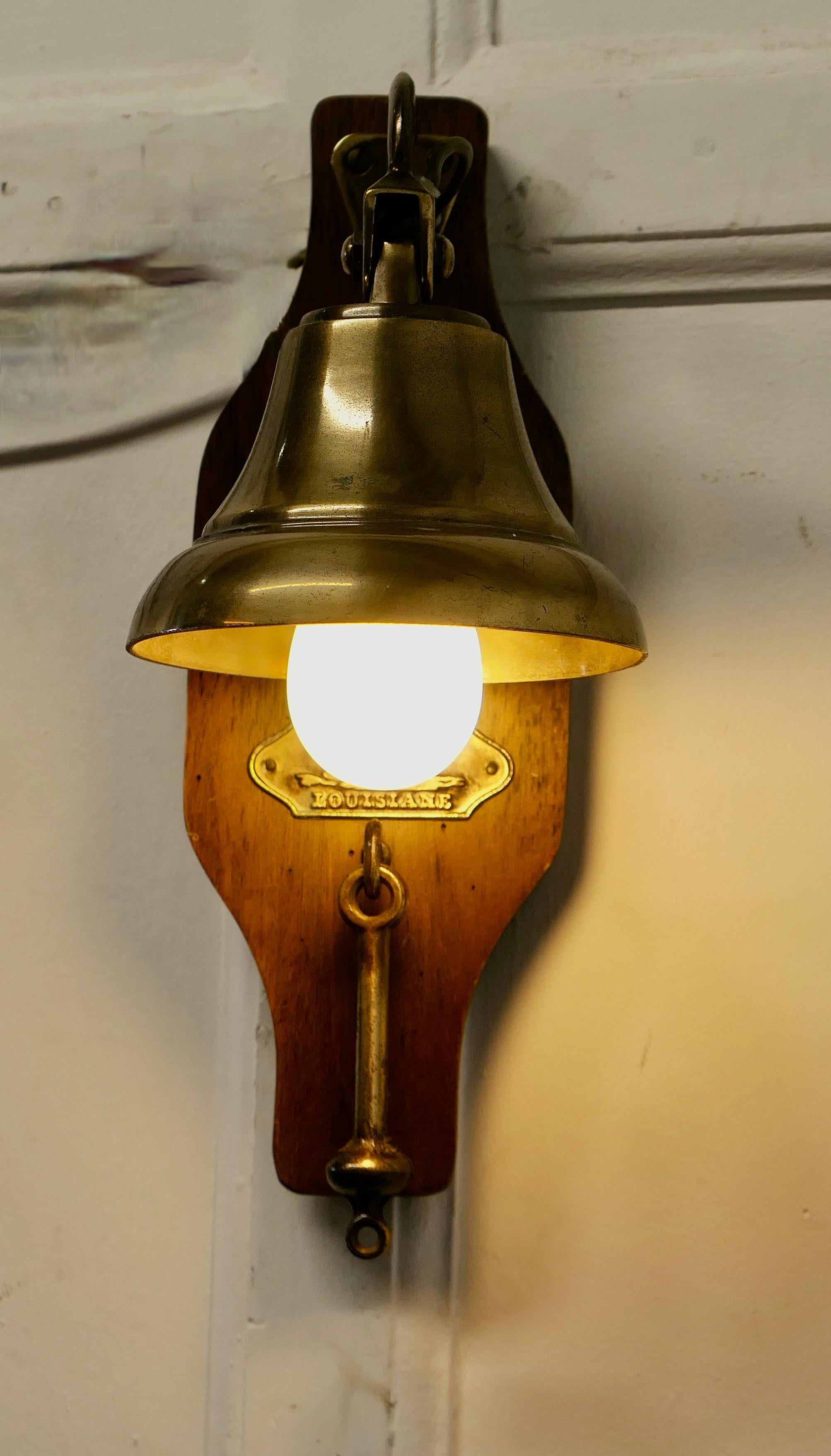 French Brass Door Bell, Porch Light on a Nautical Theme

An unusual piece, the bell is rung by tapping it with the clapper which hangs underneath, the lightbulb is concealed inside the dome of the bell
This is all set on a chestnut bracket which has