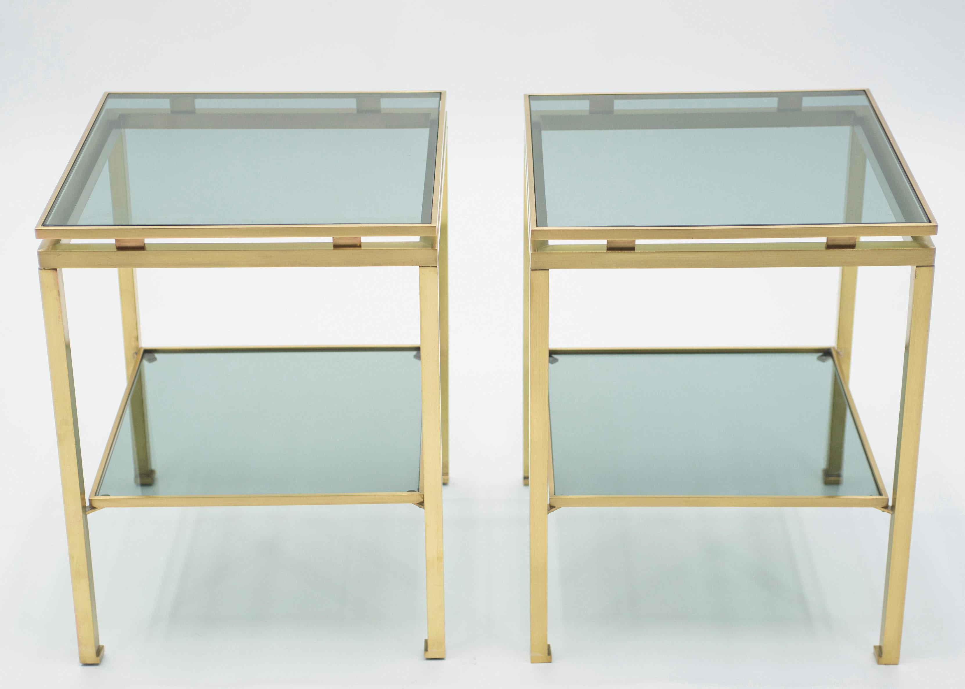 Simple lines point to this end tables French midcentury roots. Designed by Guy Lefevre for Maison Jansen, it features silky brass legs and slightly blue smoked glass tops. Its symmetry, elevated glass, and strong architectural design combine to