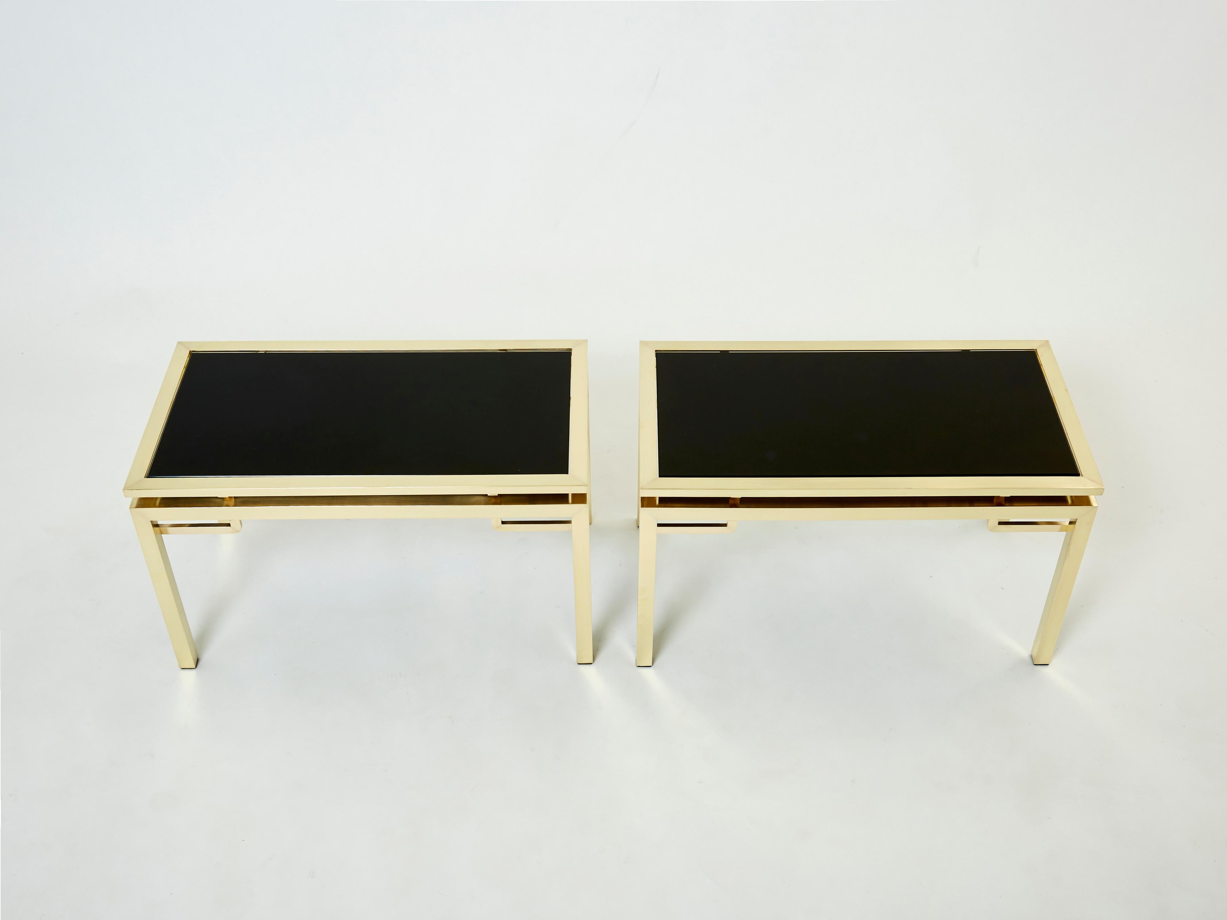 Simple lines point to these beautiful end tables or side tables french mid-century roots. Designed by Guy Lefevre for Maison Jansen, it features silky brass legs and black opaline glass tops. Its symmetry, elevated glass, and strong architectural