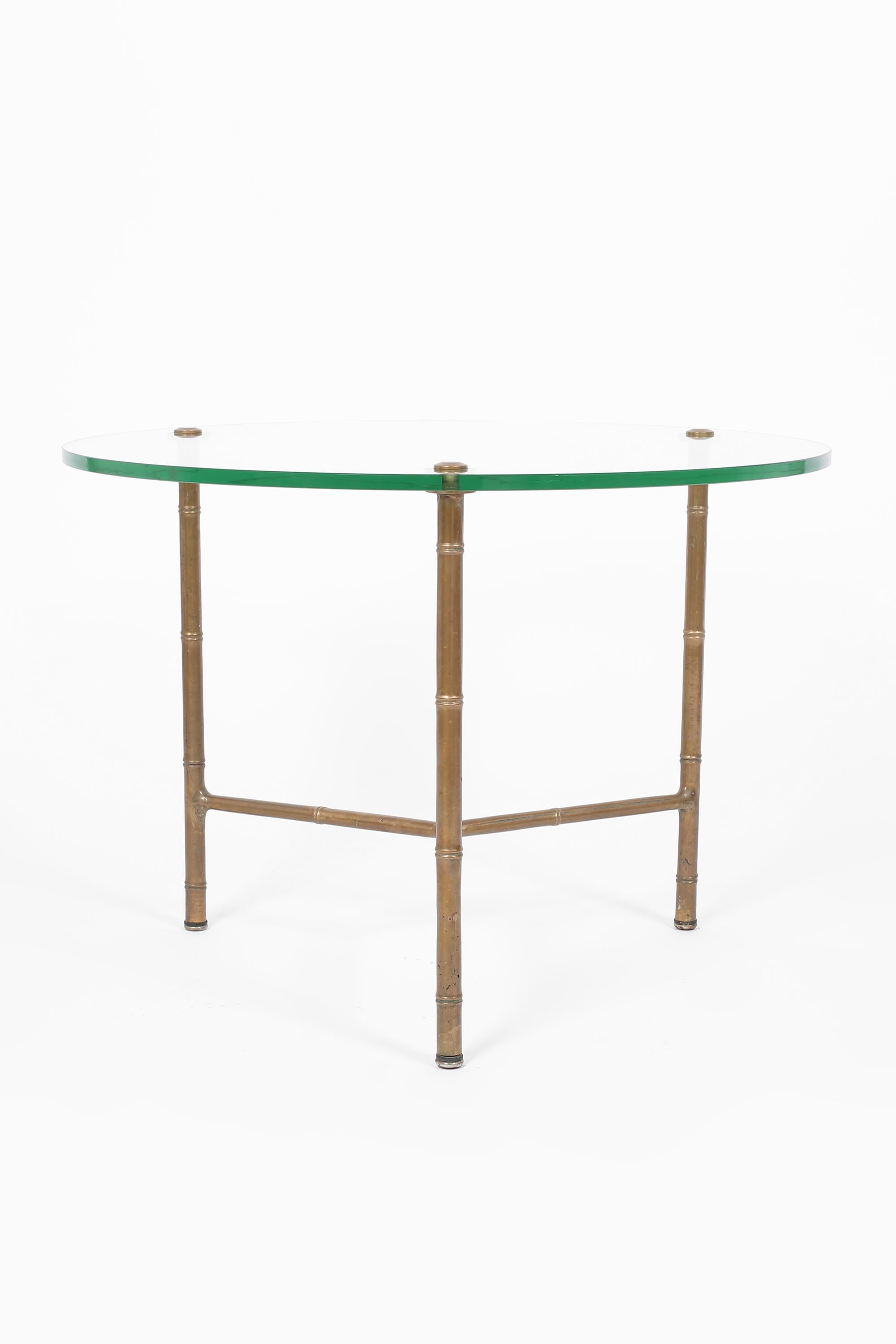 A chic circular occasional table with patinated, cast brass faux bamboo frame and original thick glass top. French, c. 1950s.