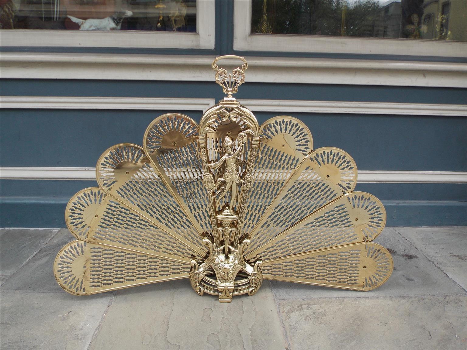French brass figural fire screen with dancing woman playing tambourine, centered foliage handle, decorative pierced chased folding fans, acanthus motif, and terminating on a scrolled floral beaded swag base with mythological figural medallion, Early