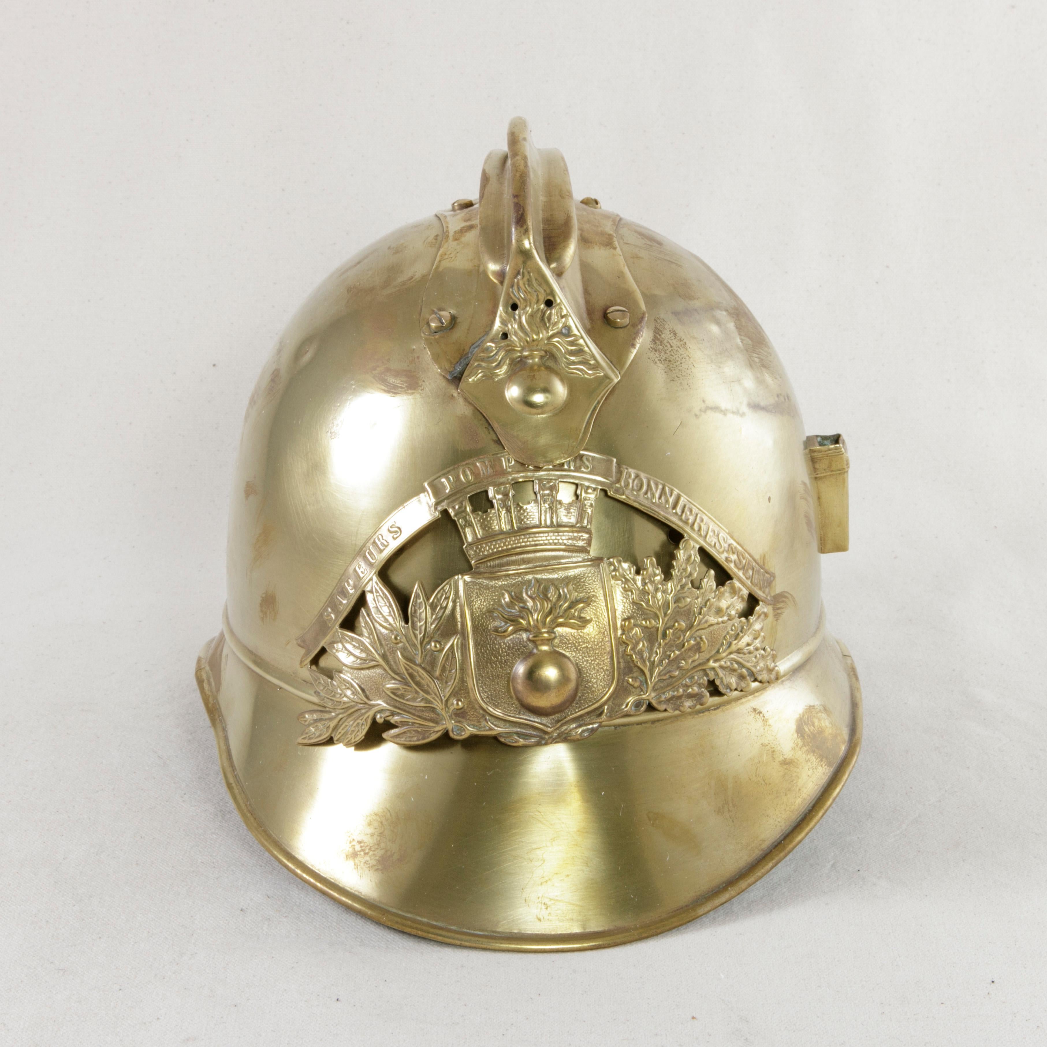 This French brass fireman's helmet from the turn of the 20th century takes the form of a French military helmet, a style frequently seen during the First World War. The front plate of the helmet bears the classic French fireman symbol of a flaming