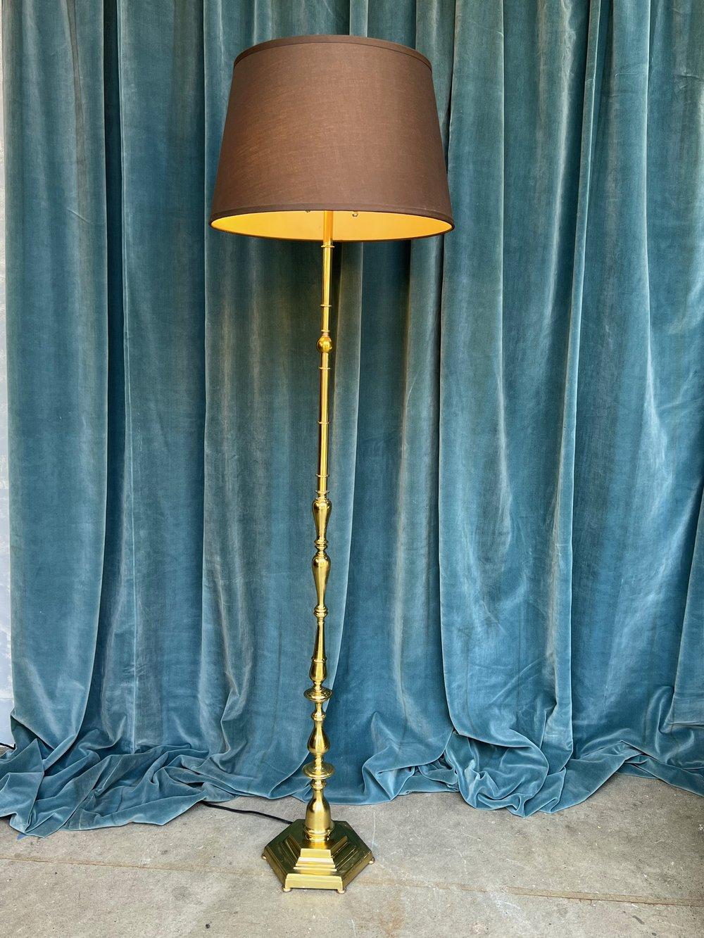 A beautiful French brass floor lamp from the 1940s featuring an elegant design with a footed hexagonal base. This vintage piece is a striking addition to any decor, catching the eye with its timeless appeal. While there is some tarnishing and wear
