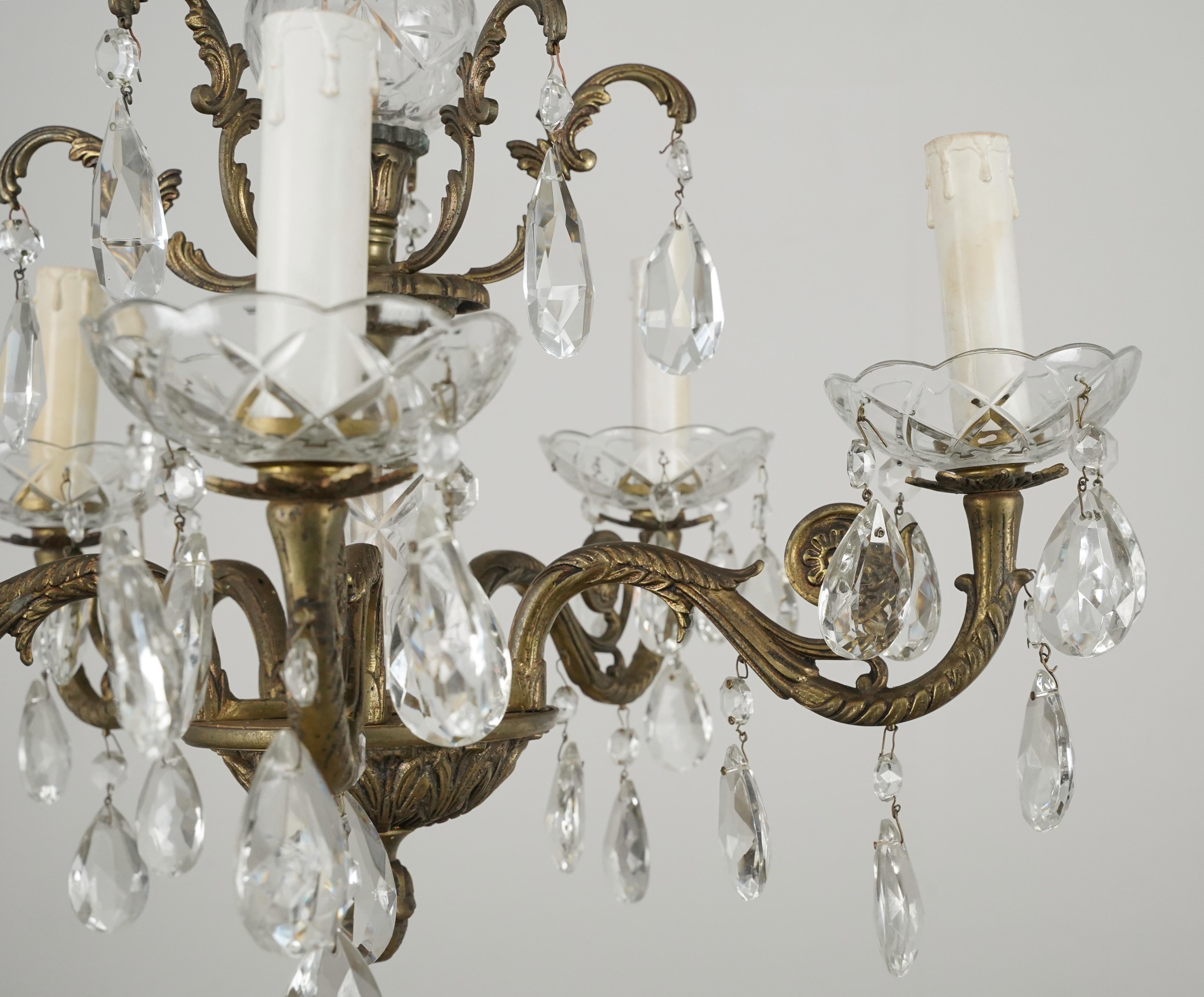 Lampadario in stile francese con struttura in ottone decorato, bobeches ed elementi in cristallo e cristalli ottagonali e a goccia. La catena è realizzata in acciaio placcato ottone. Questa lampada richiede cinque lampadine E-12 a candelabro. Buone
