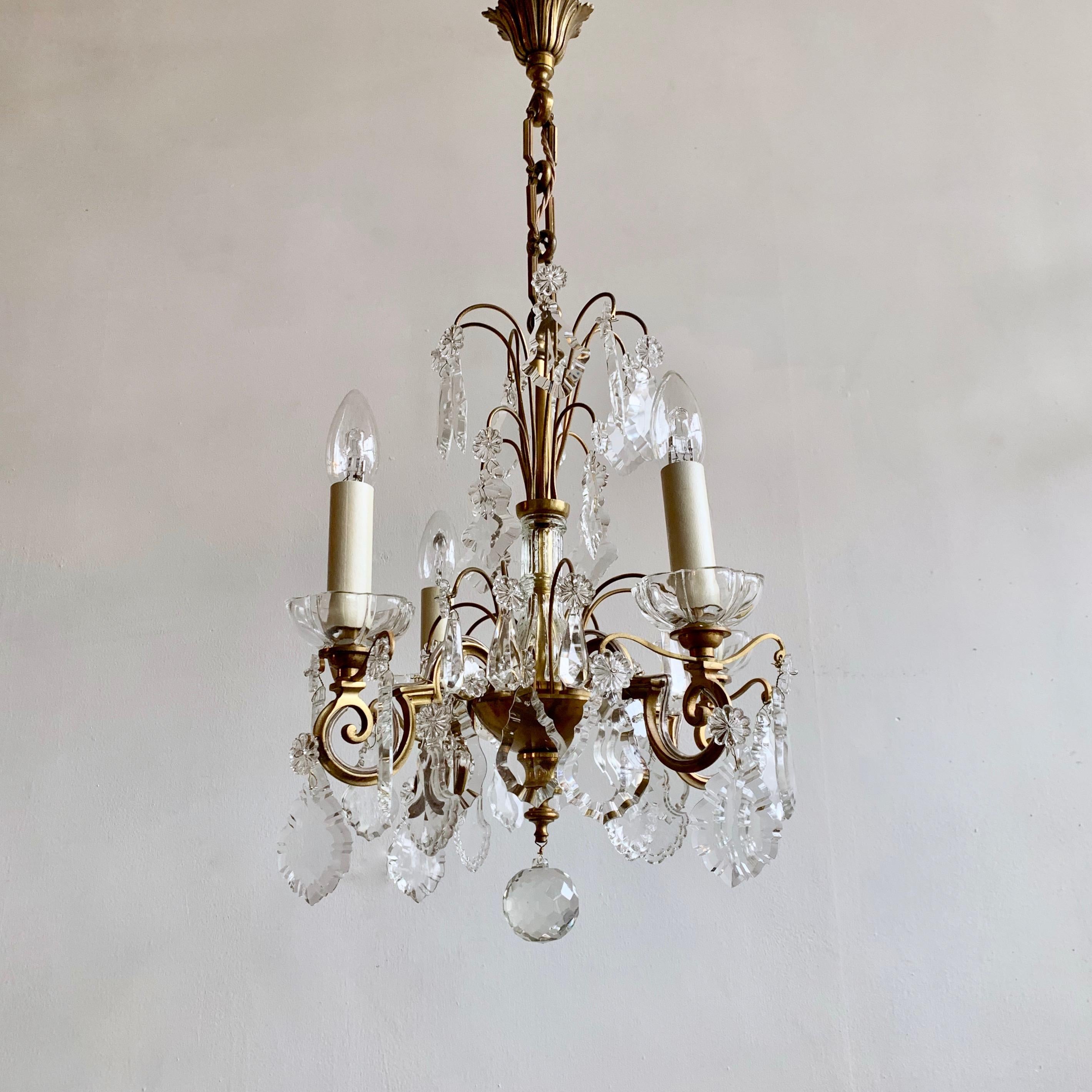 This small Louis XIV style chandelier originates from early 1900s, France. Retaining it’s original glass it is a stunning center piece. The brass chandelier frame has varied natural patina and unique glass bobéche pans which will reflect the light.