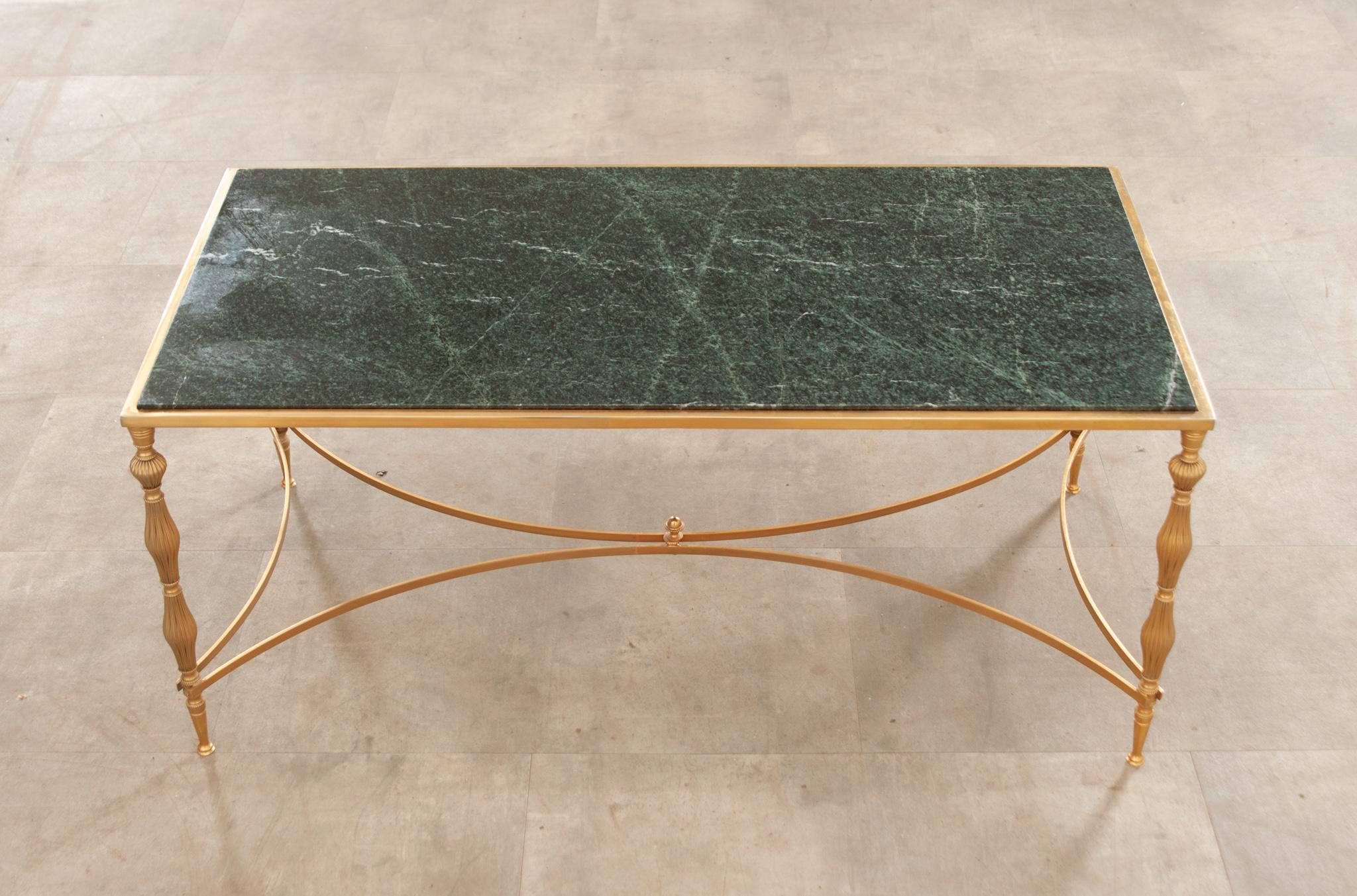A beautiful French brass low table with a deep green polished marble top, circa 1970, featuring expertly turned and fluted legs connected to a curved stretcher with a decorative finial. Vibrant and wonderfully patinated. This fantastic little table