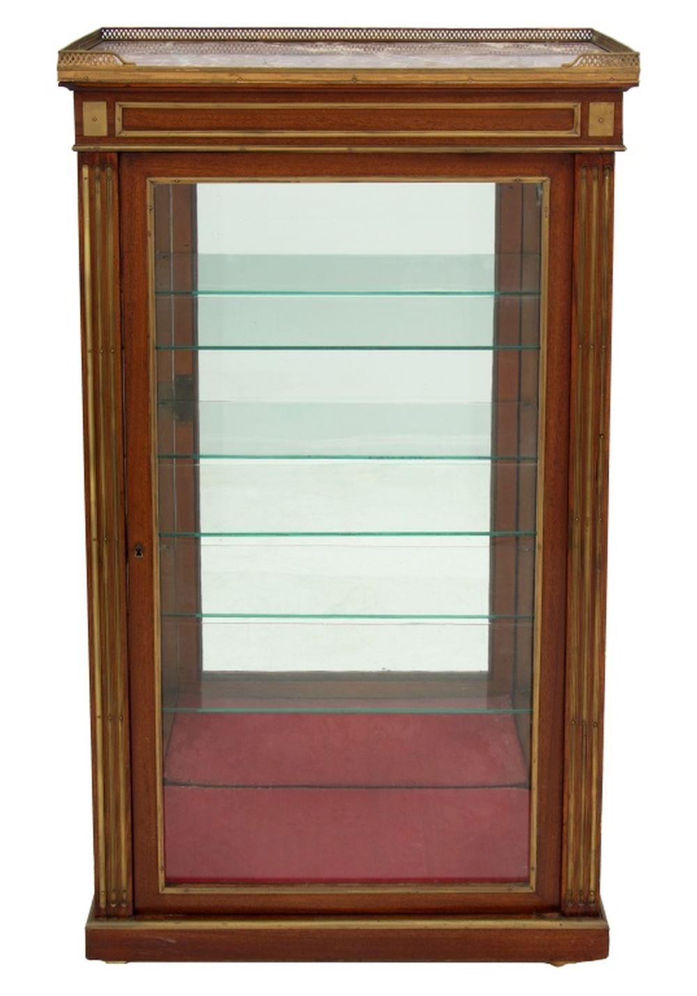 Vitrina francese in ottone montata su mogano e marmo rosso, fine del XIX secolo. Il piano rettangolare a tre quarti di galleria sopra una porta vetrata racchiude tre ripiani in vetro regolabili, affiancati da pilastri scanalati su uno zoccolo e