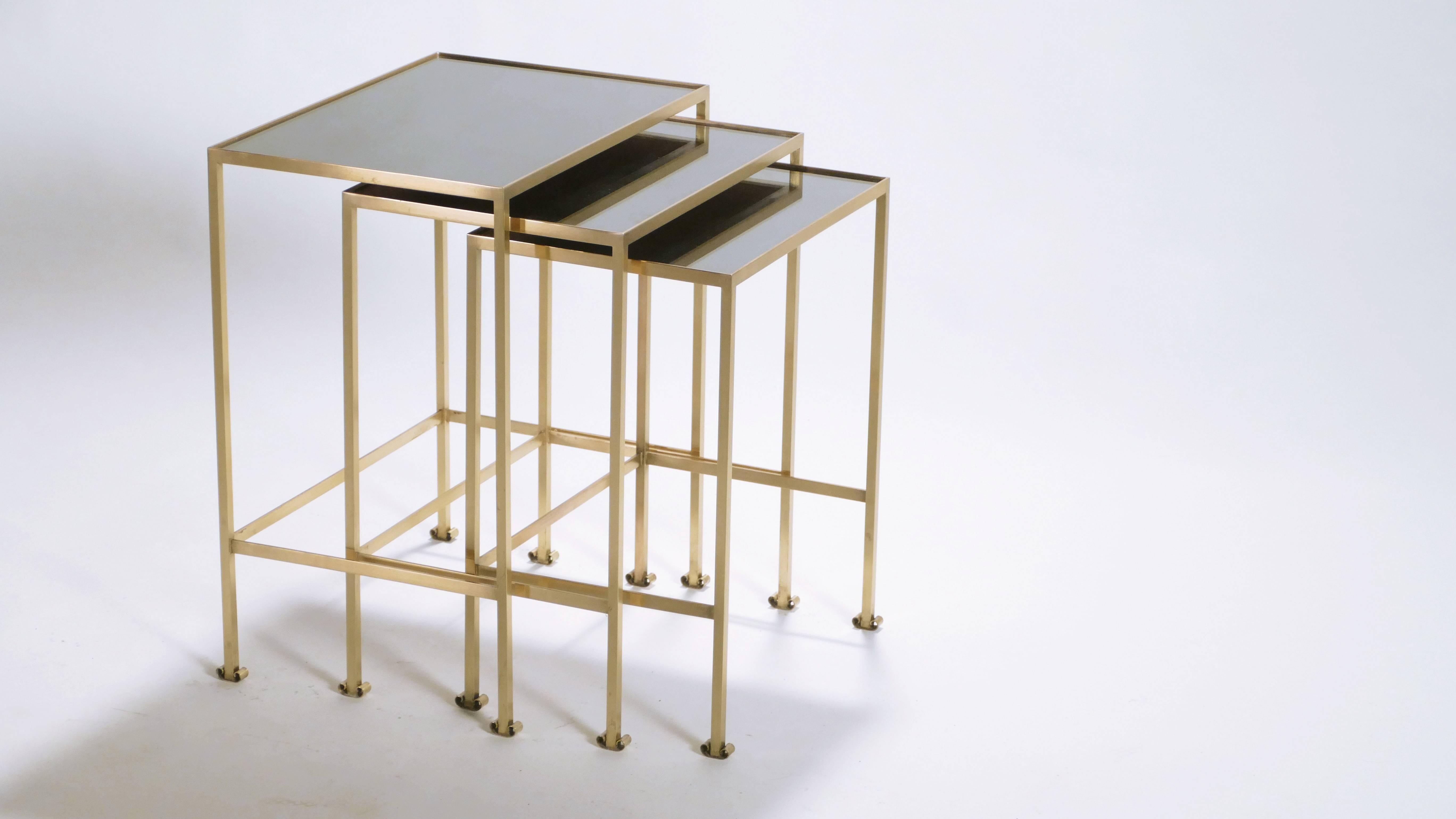 Add a decorative, chic element to your interior with this set of vintage nesting tables from the 1960s. The set embodies the simple, straight lines of French neoclassicism, with smooth black opaline surfaces and beautiful brass feet that end in a