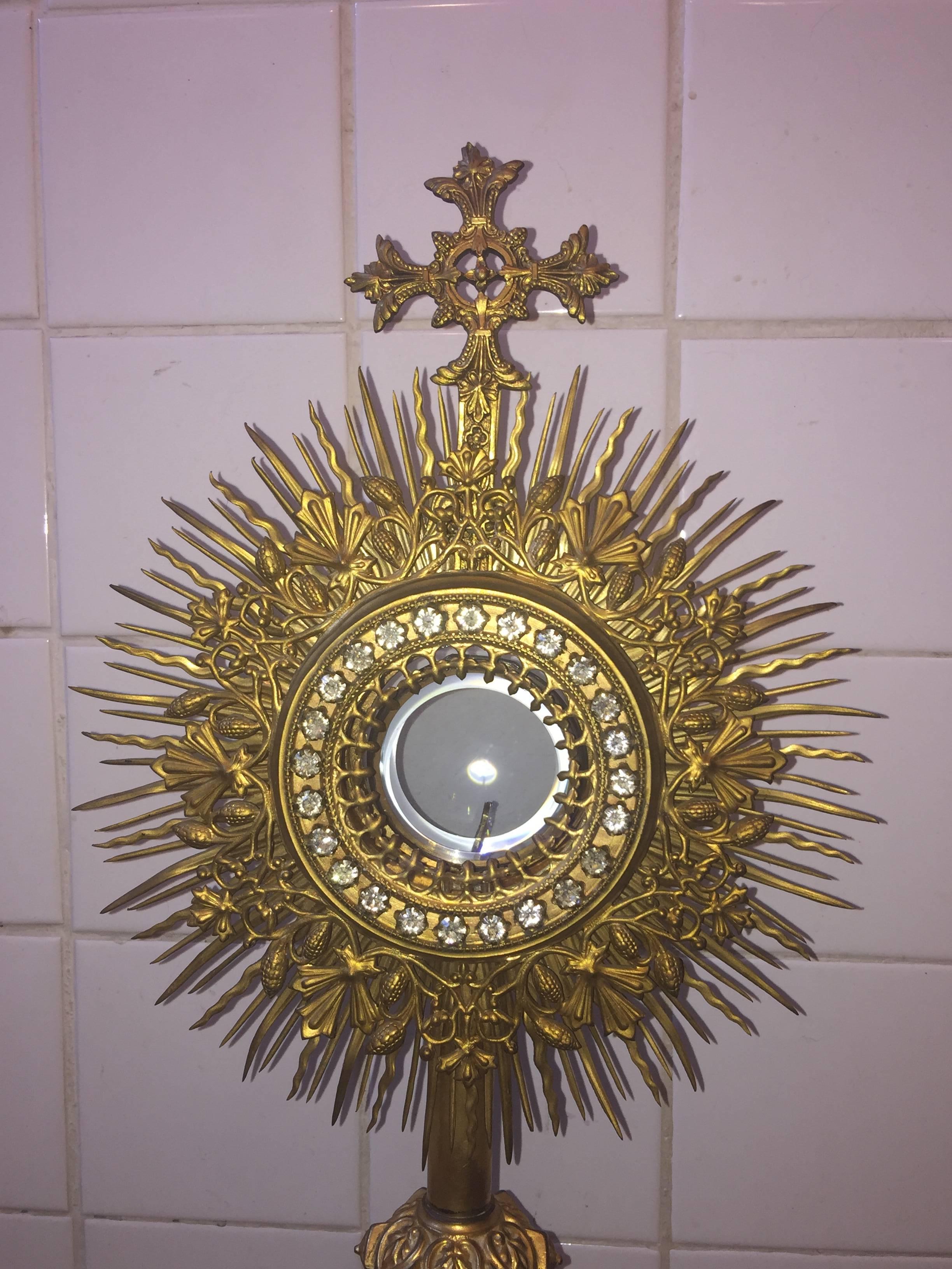 French brass starburst monstrance fitted with round frame of brilliant set paste stones surrounding glass circular centre fitted with locket style beveled glass centre that slides inside to magnify your image you wish to use. Decorated with a
