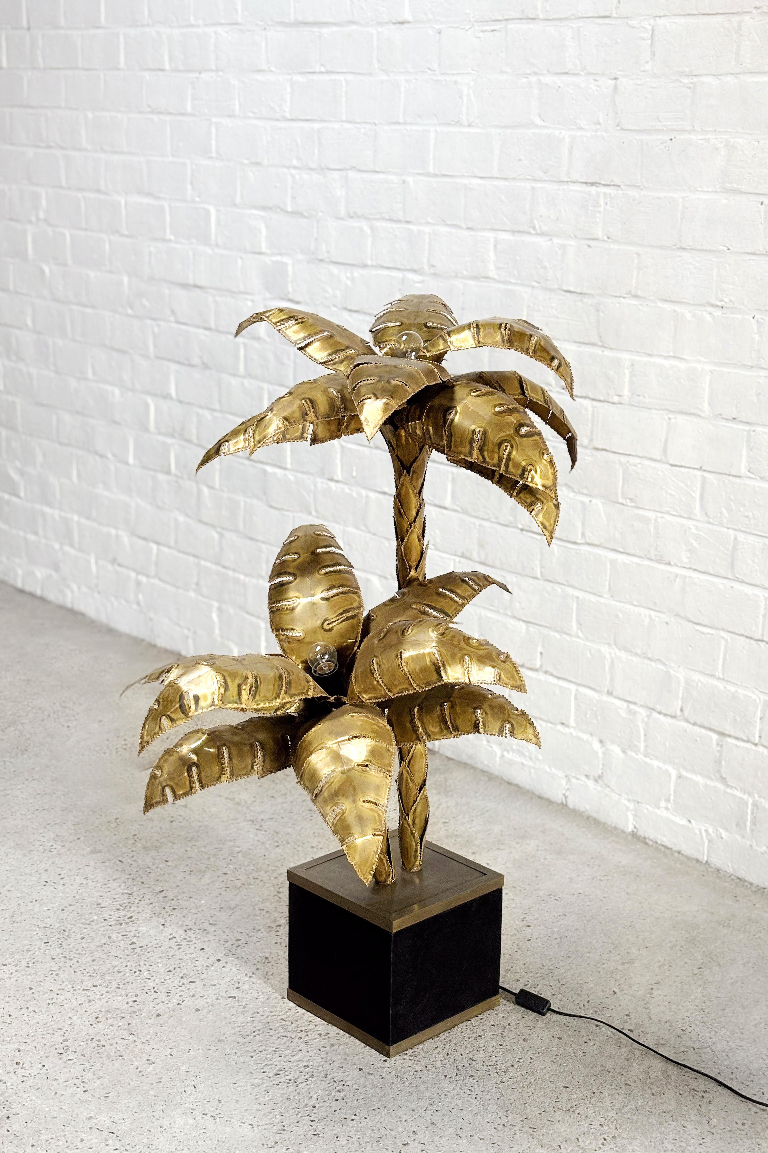 A stunning Maison Jansen palm tree floor lamp, 1970s. This model features two light points. The lamp has been constructed by hand using brass sheets overlapping each other to mimic the leaves and trunk of the plant. Of lovely proportions, this