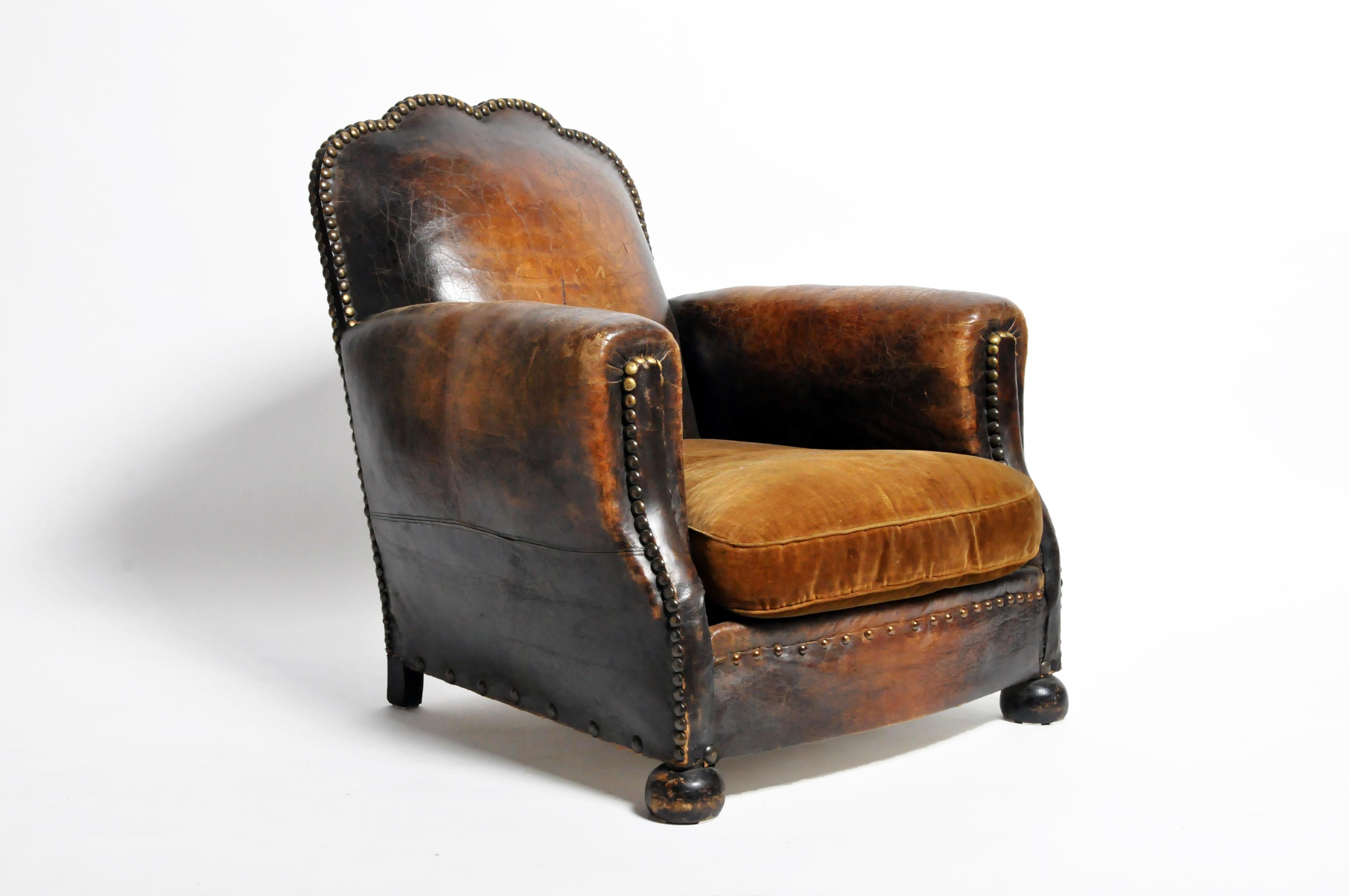 Handsome French leather club chair made, circa 1900. This chair features a beautifully aged patina on the leather and woodwork. The original leather seat cushion has been replaced with velvet upholstery which can be changed according to customer