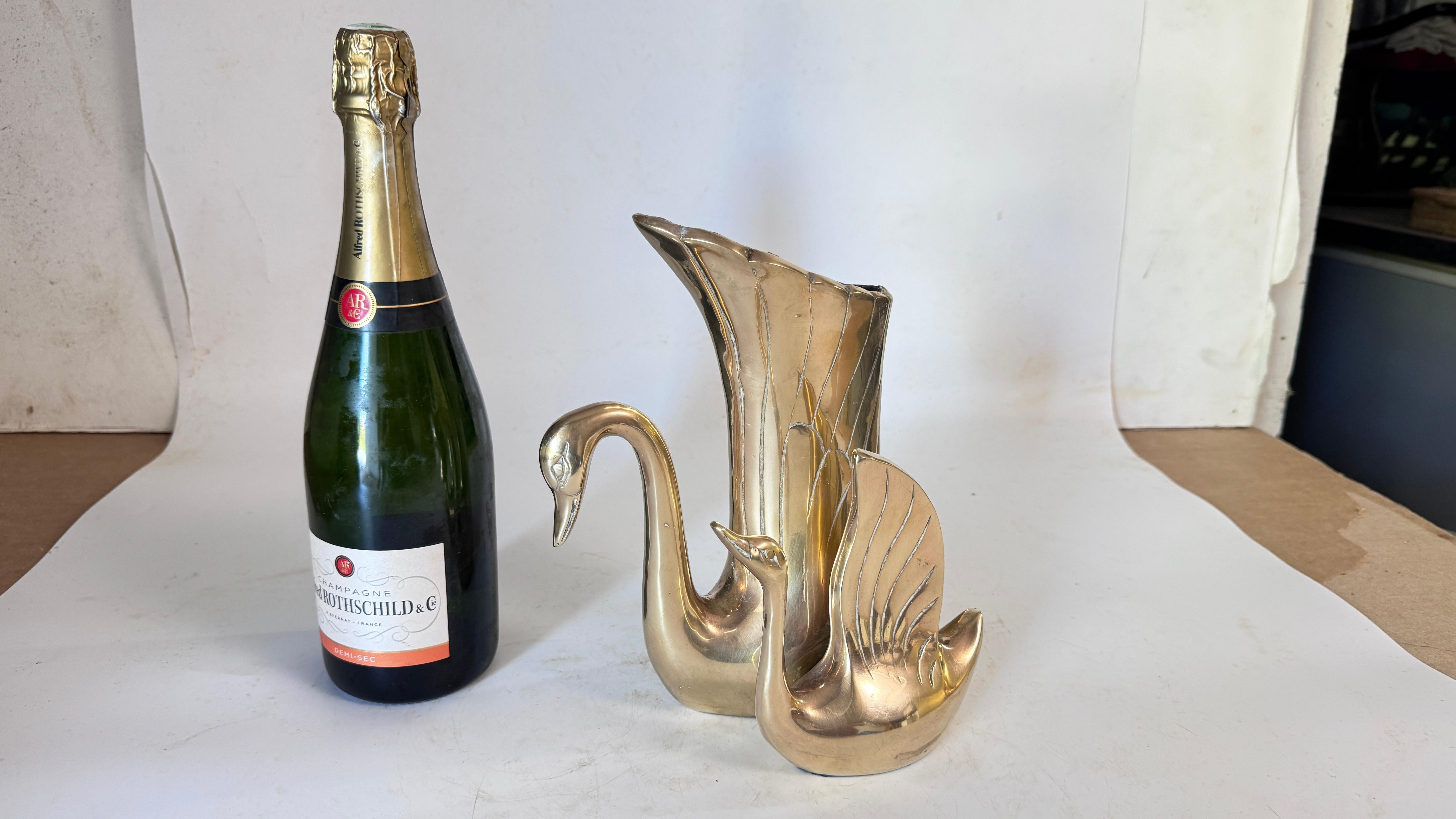 This is a French decorative brass vase from the 1970s, designed as a sculpture of two swans. The body of one swan elegantly forms the vase, while the other completes the sculptural ensemble. Crafted from high-quality polished brass, this piece
